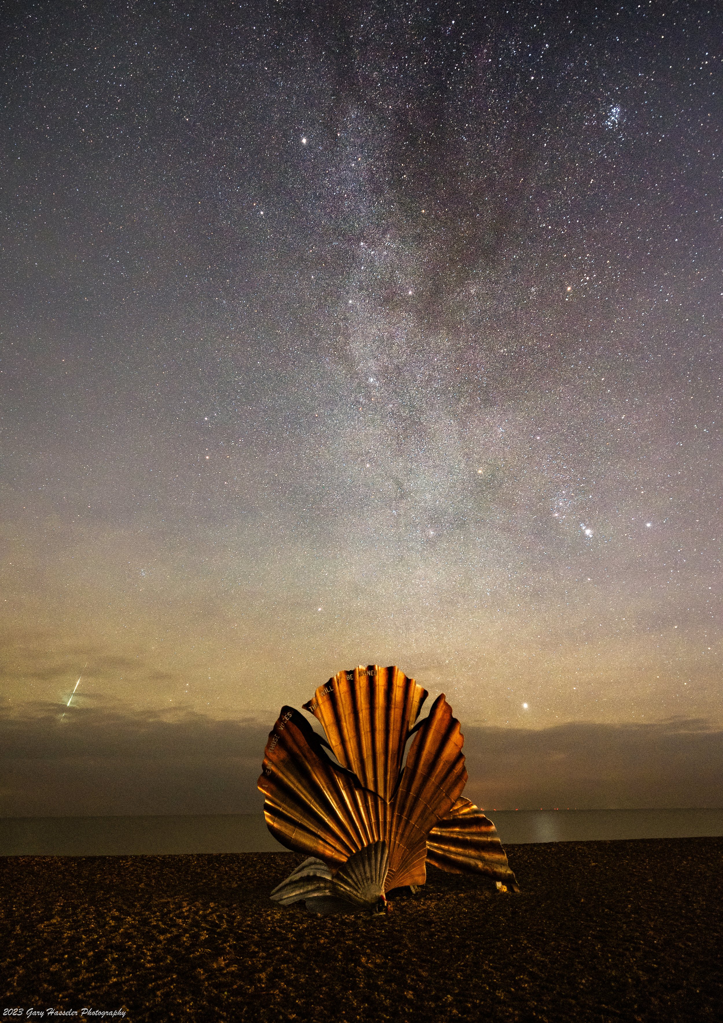 The Milky Way and a prominent Geminid meteor over the scallop sculpture on Aldeburgh beach. December.