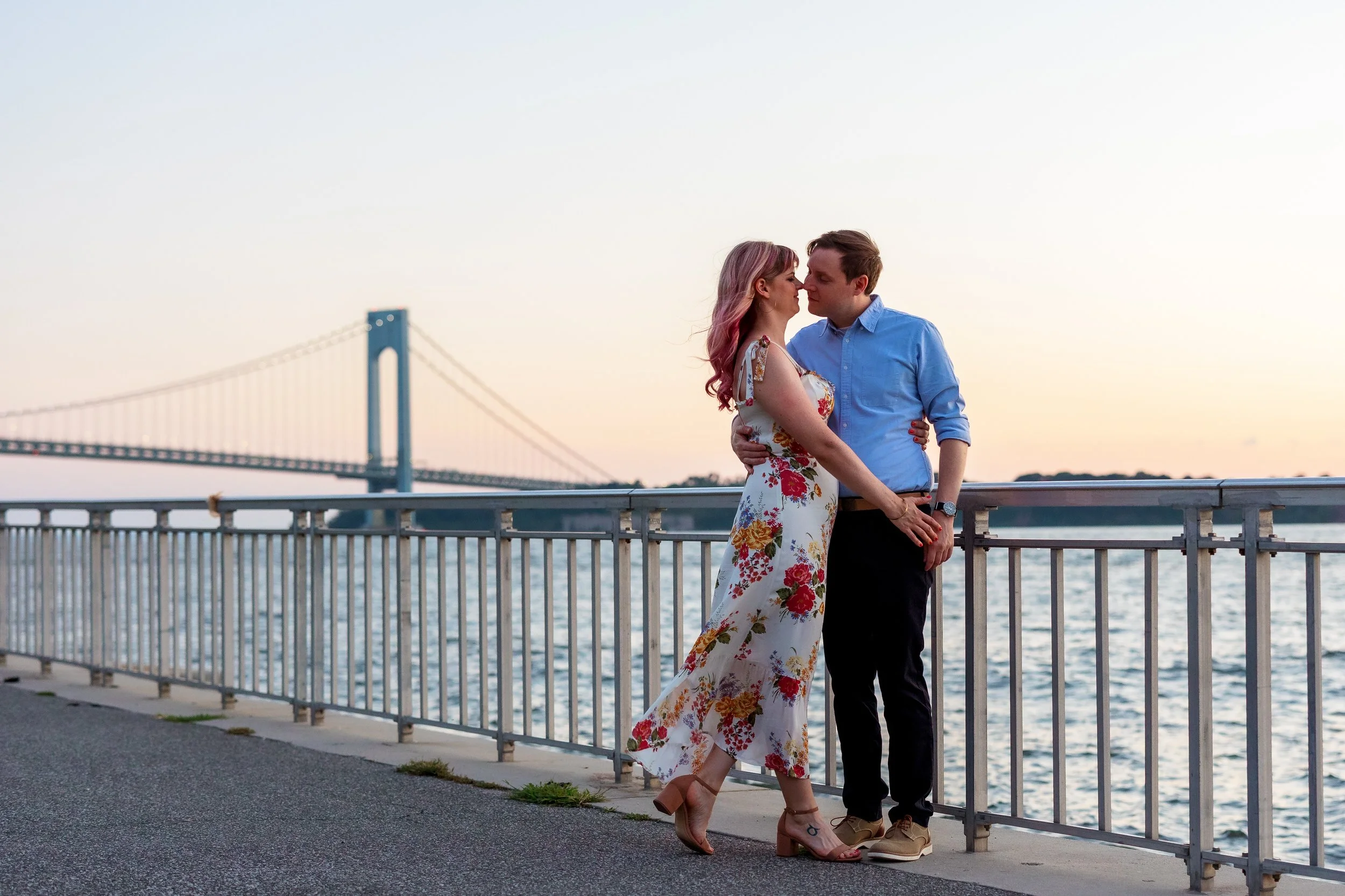 A couple leaning in about to kiss while standing at the edge of a river 