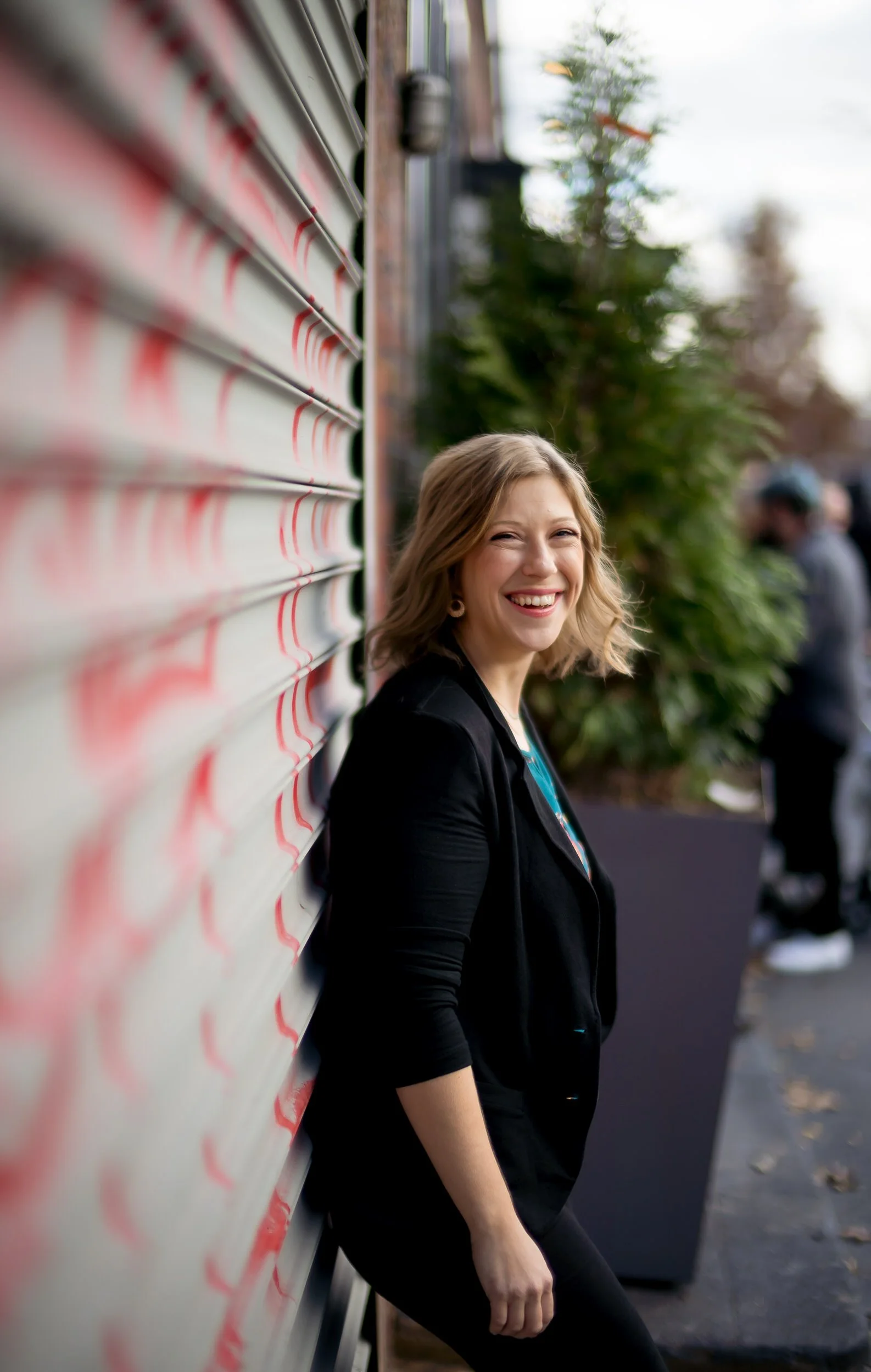 Sarah standing against a red and white wall smiling