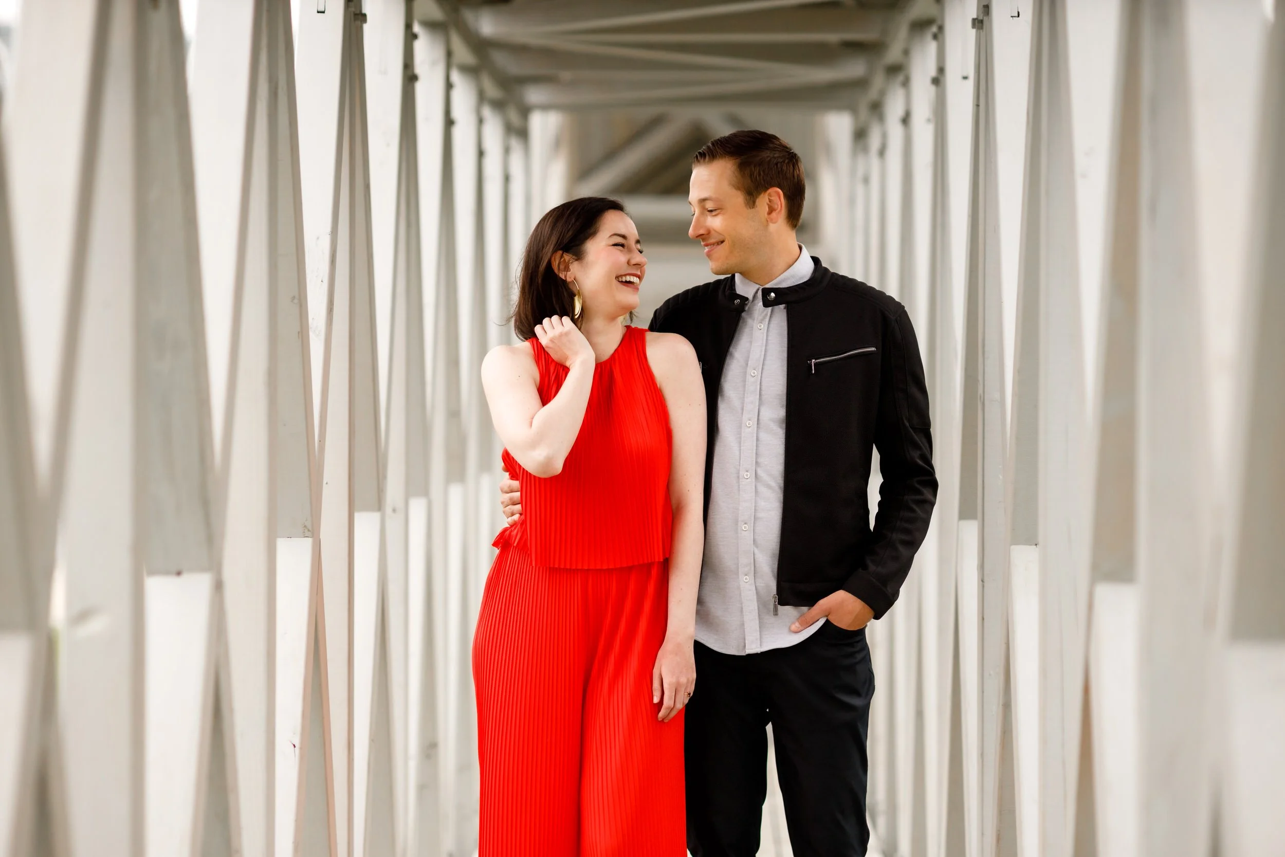 A couple standing close and smiling at each other in a narrow hallway 