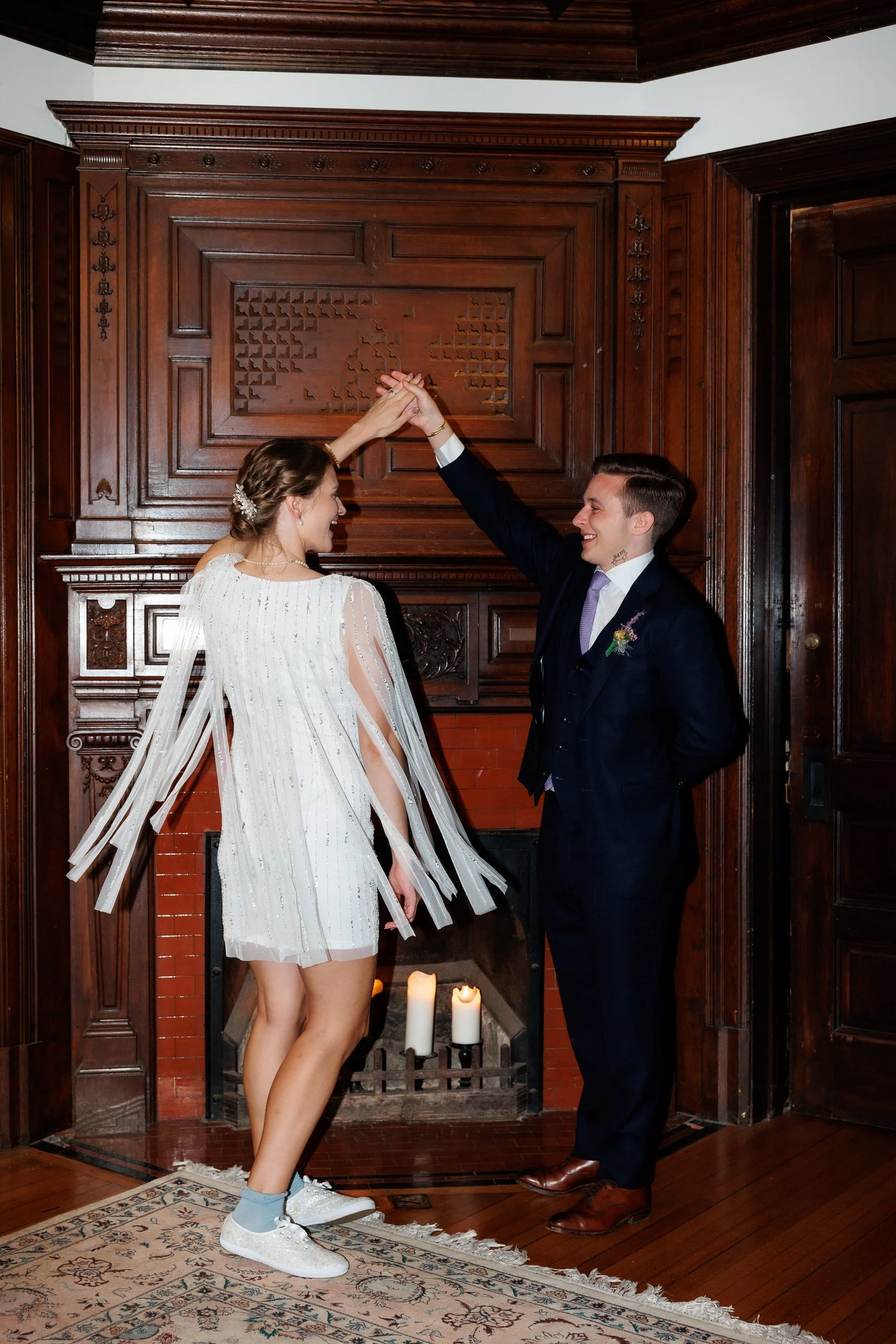 Newlyweds dancing next to a fireplace 