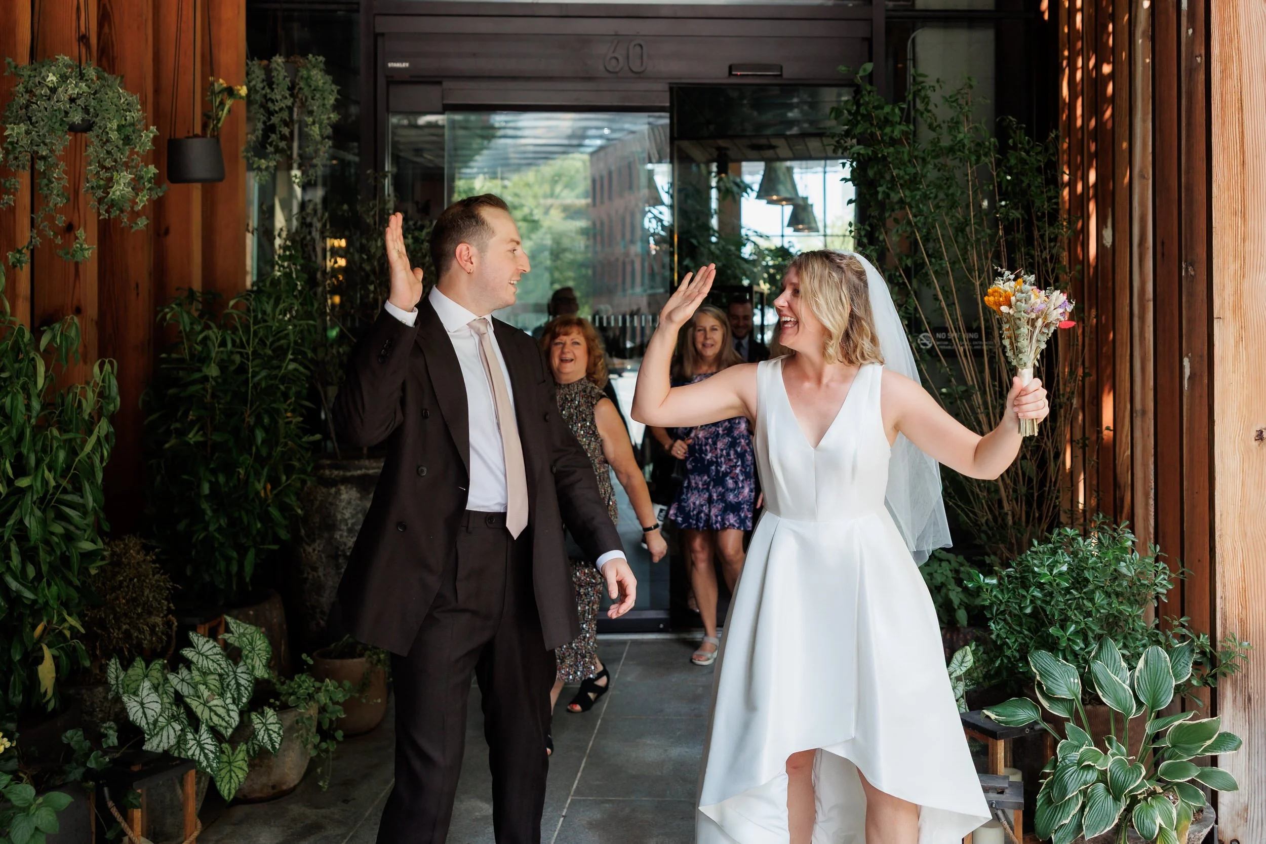 A wedding couple as they go to high five each other 