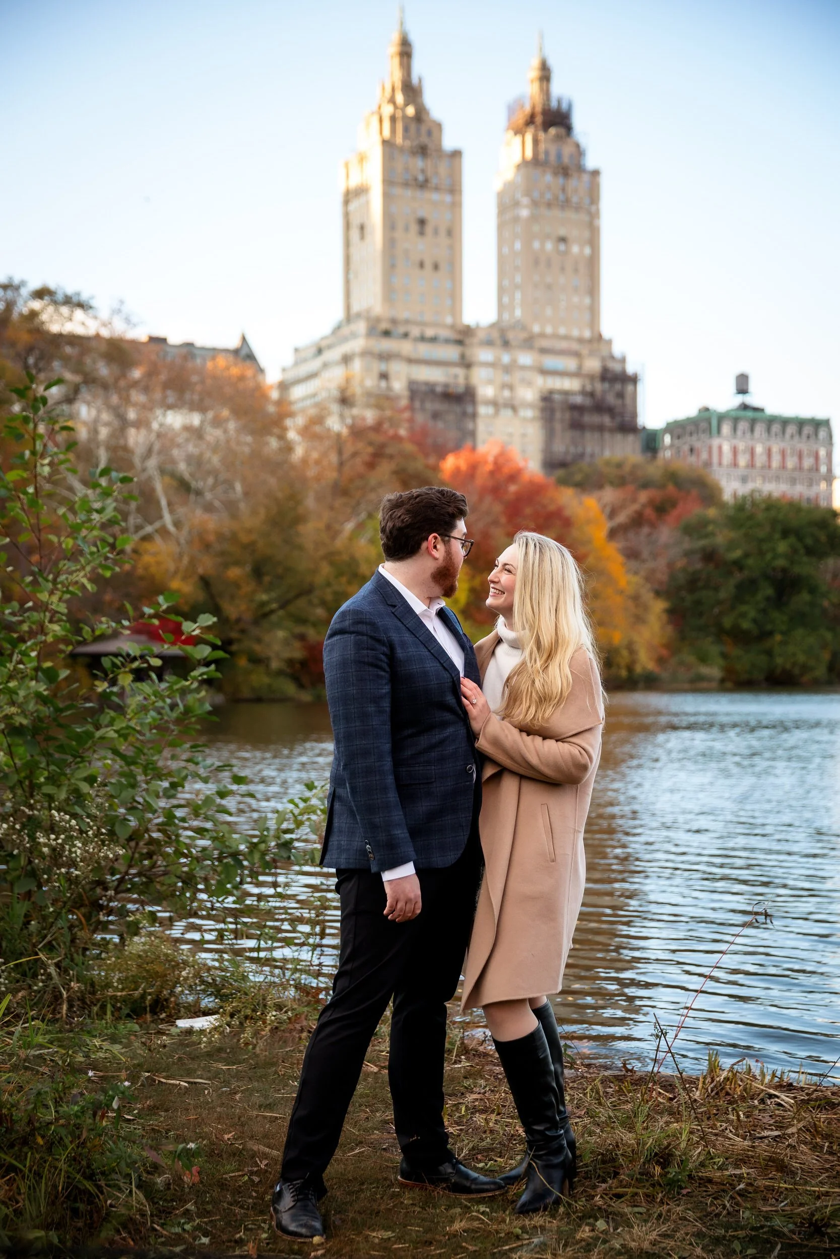 A couple laughing and standing close together with a city skyline behind them 