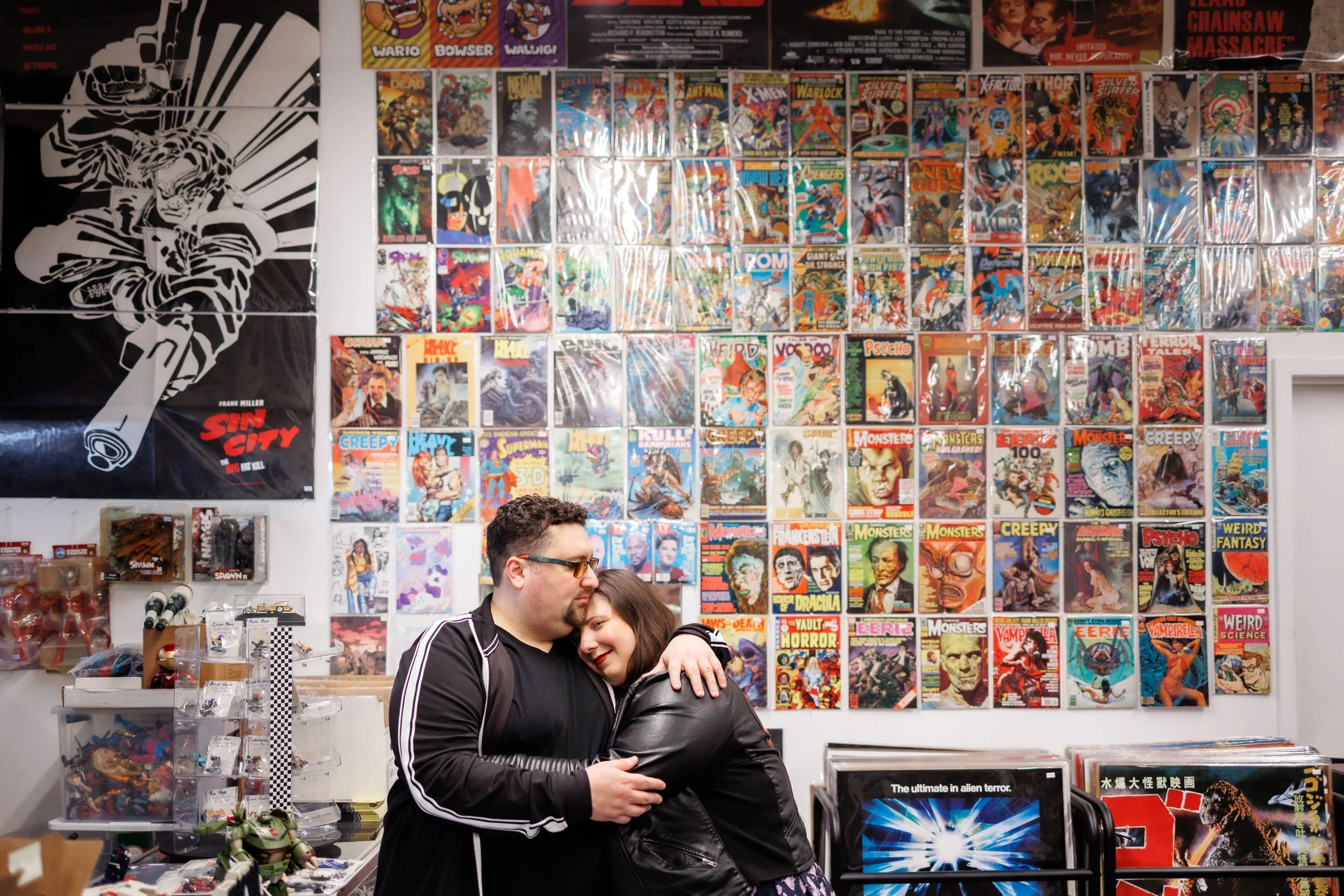 A person hugging their partner with a wall of comic books behind them 