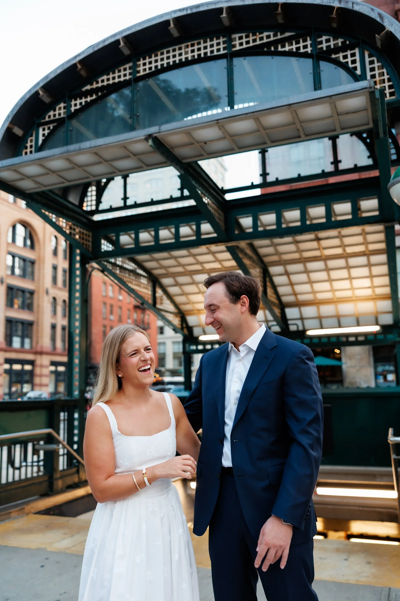 A couple laughing as they stand in front of a subway station 