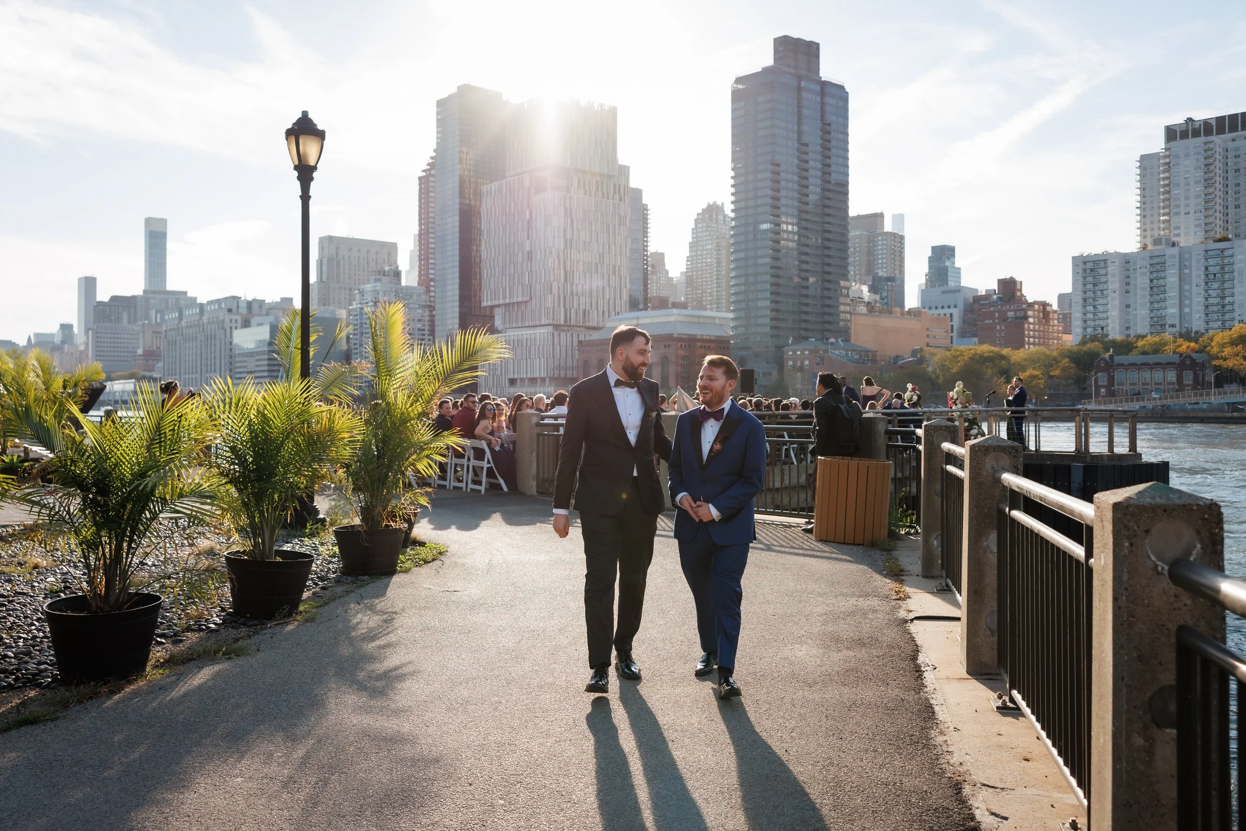 Newlyweds holding hands and walking on a path along a river in a city 