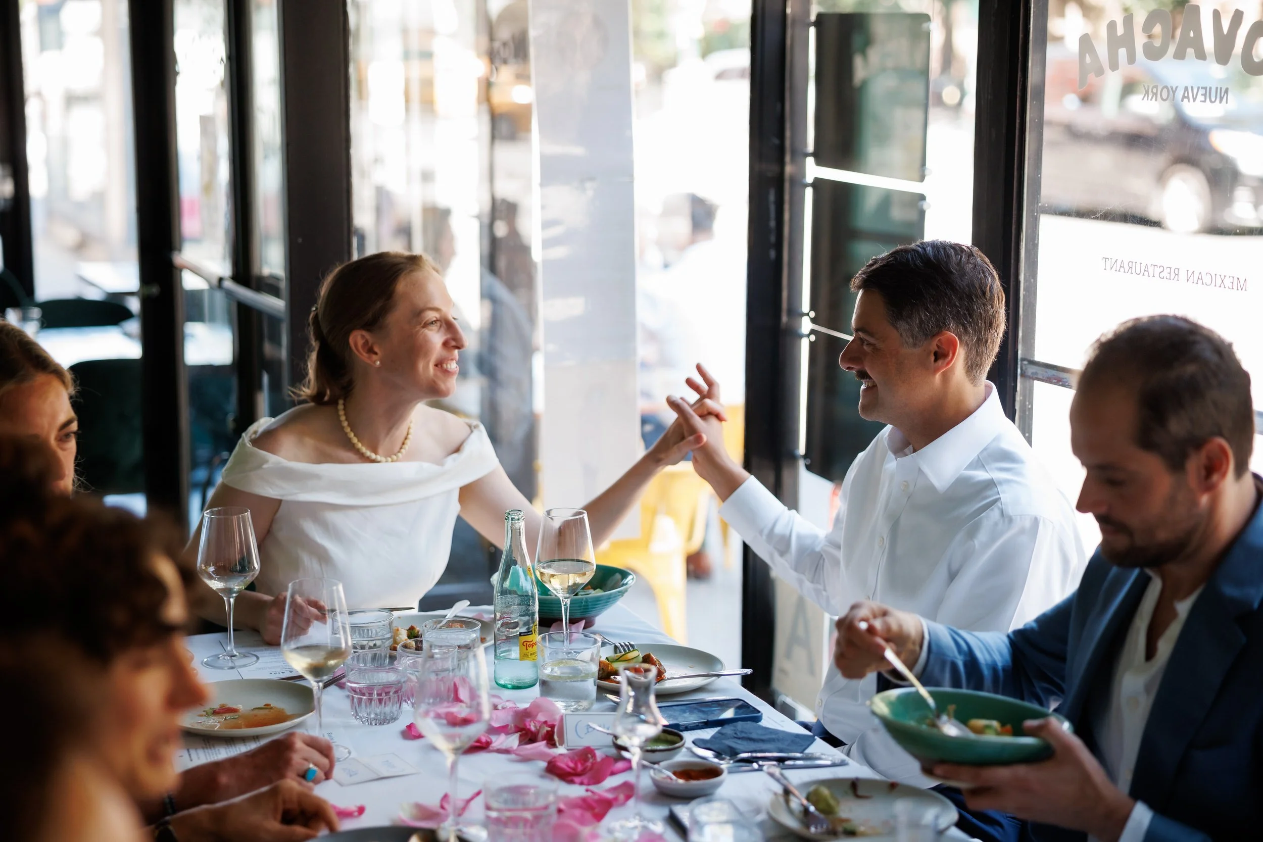 A newlywed couple with their finger's intertwined as they talk at their reception 