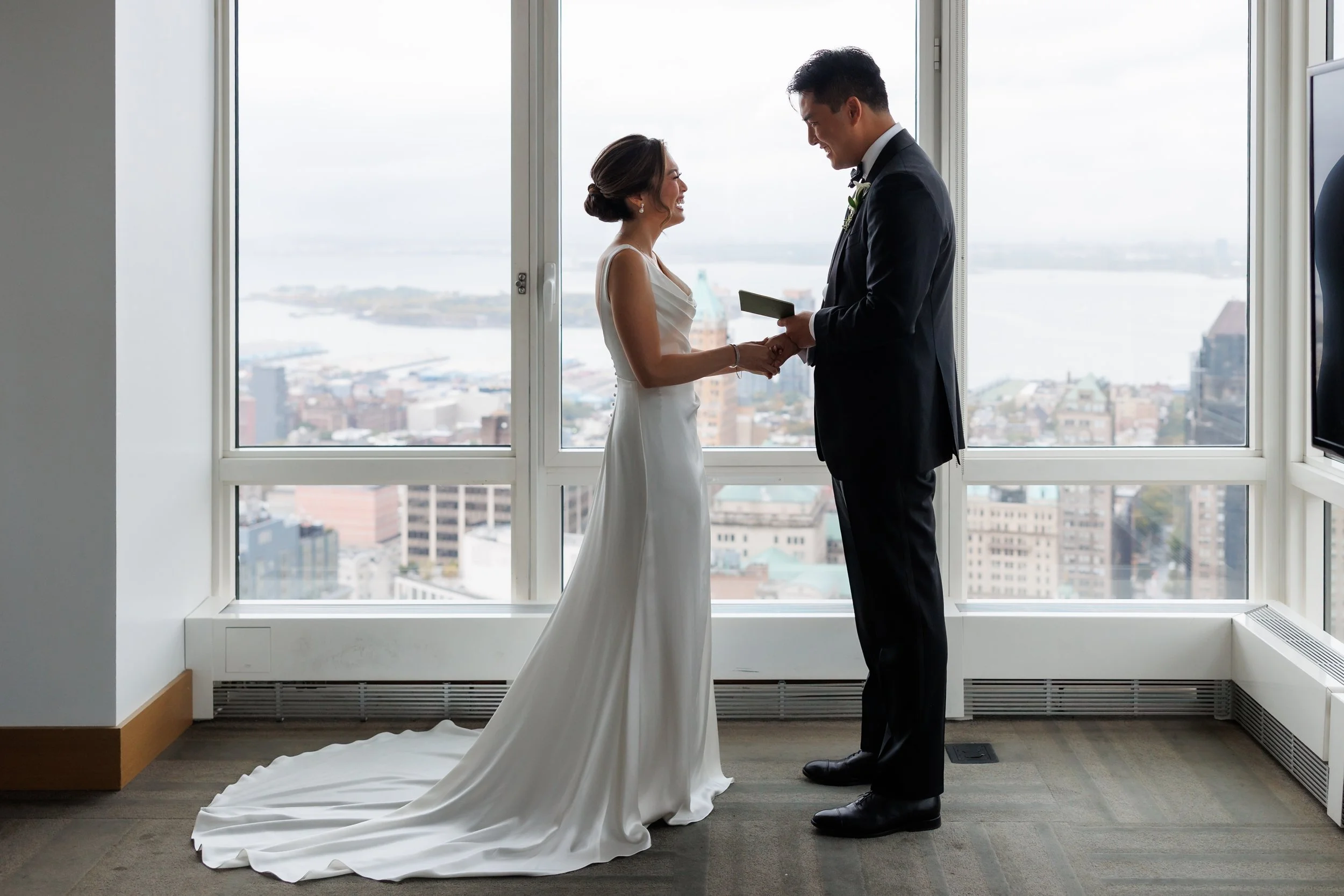  Couple exchanges private vows in front of large window overlooking the East River 