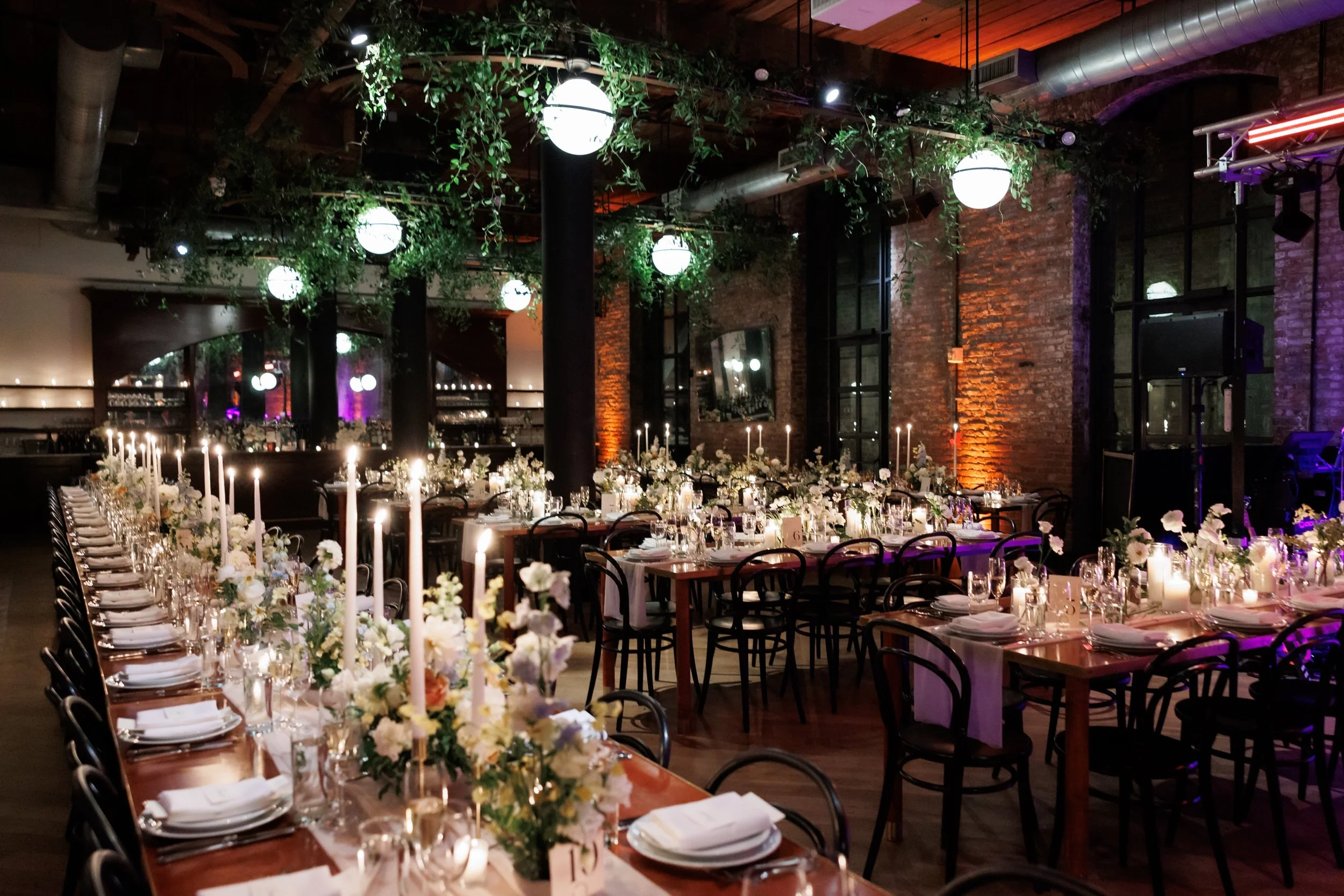  Wedding reception dinner tables decorated with tall taper candles, flowers, and lots of greenery 