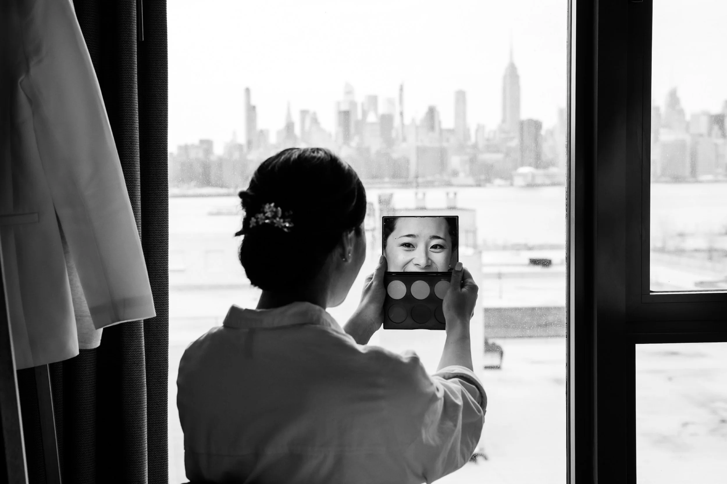 Woman looks into make-up mirror while getting ready for wedding