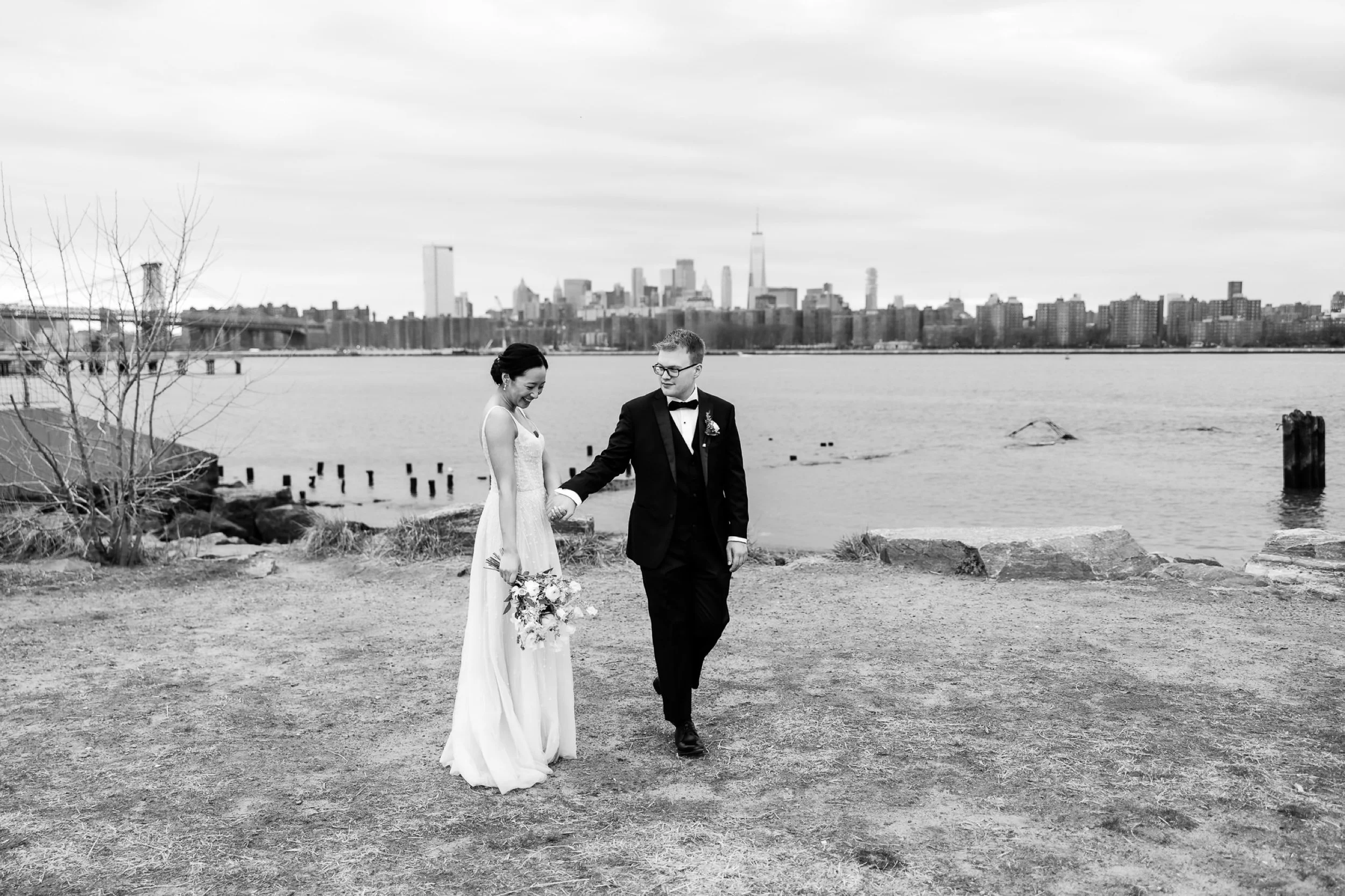 Groom takes the hand of his bride in front of the NYC skyline