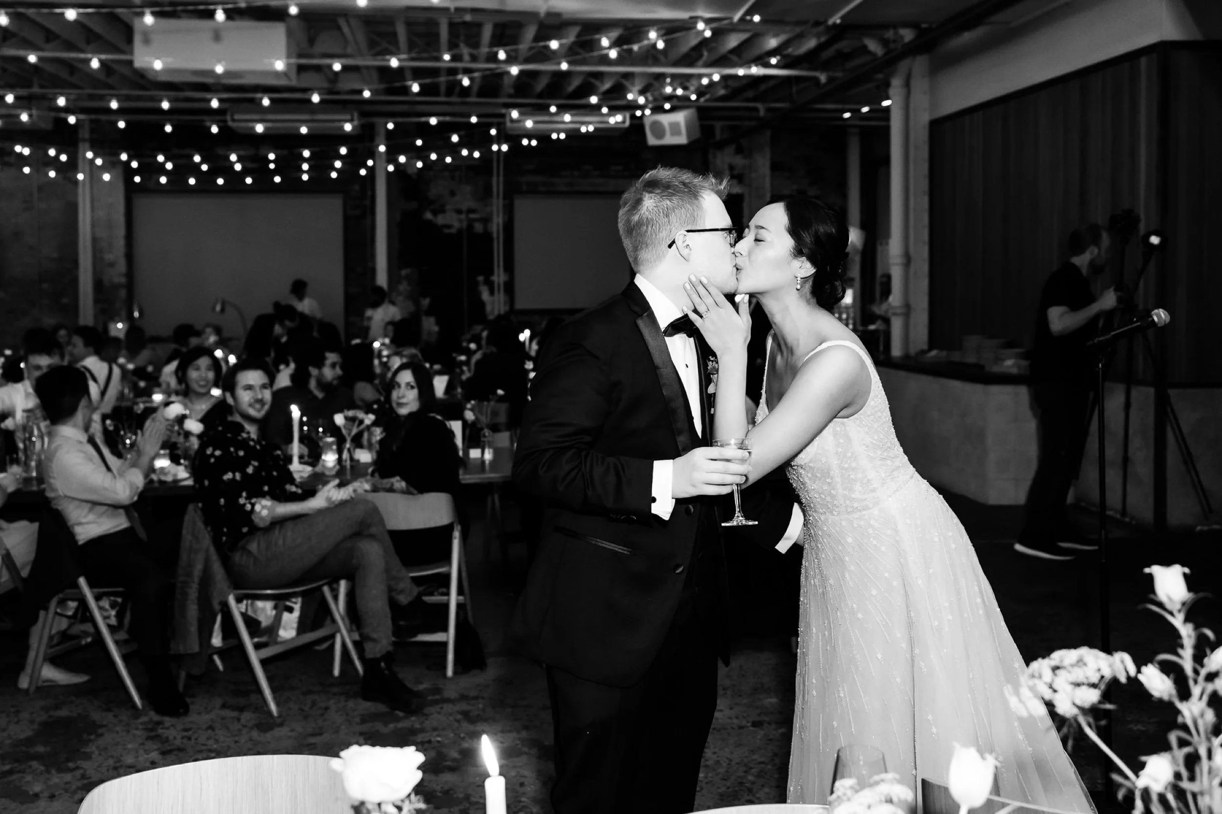 Couple sneaks a kiss during dinner at their wedding at Rule of Thirds