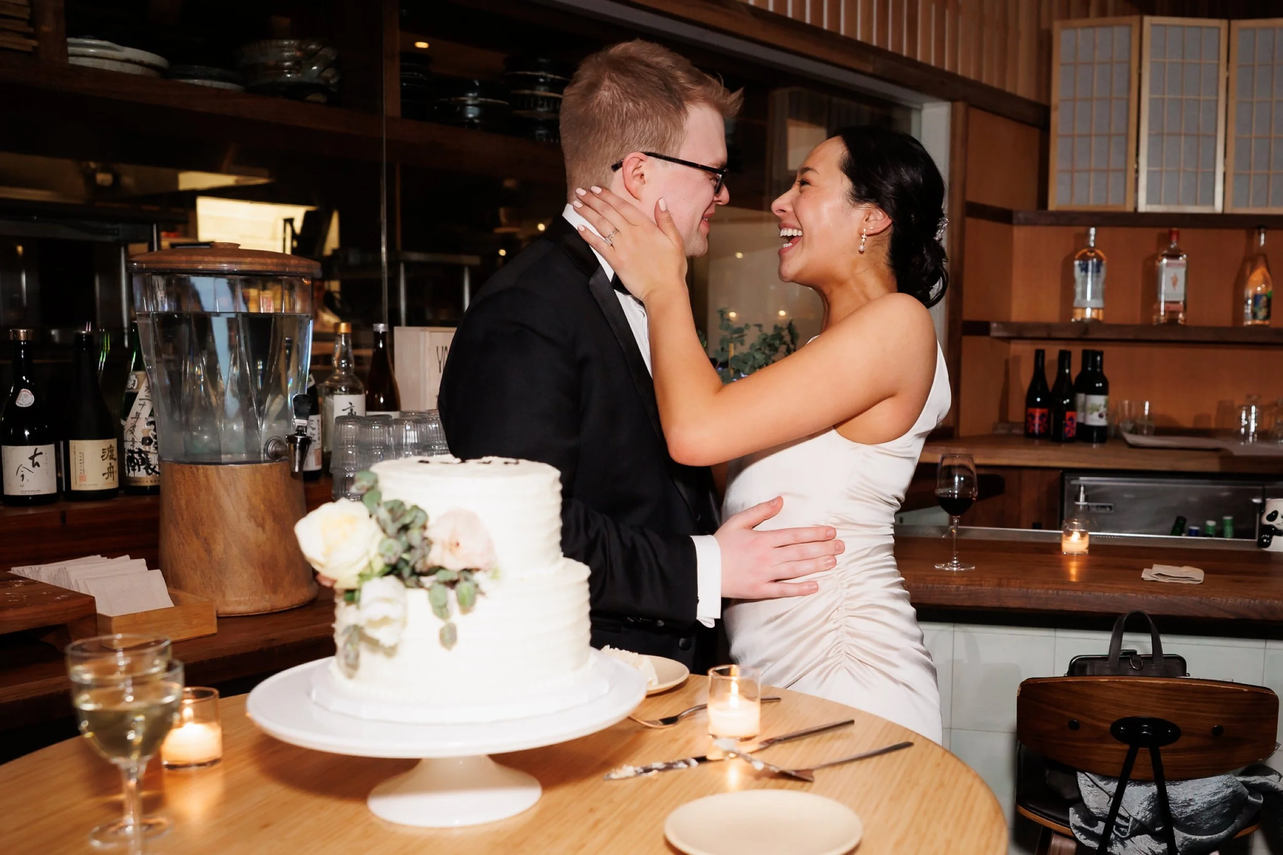 couple looks at each other and kisses each other after cutting their wedding cake