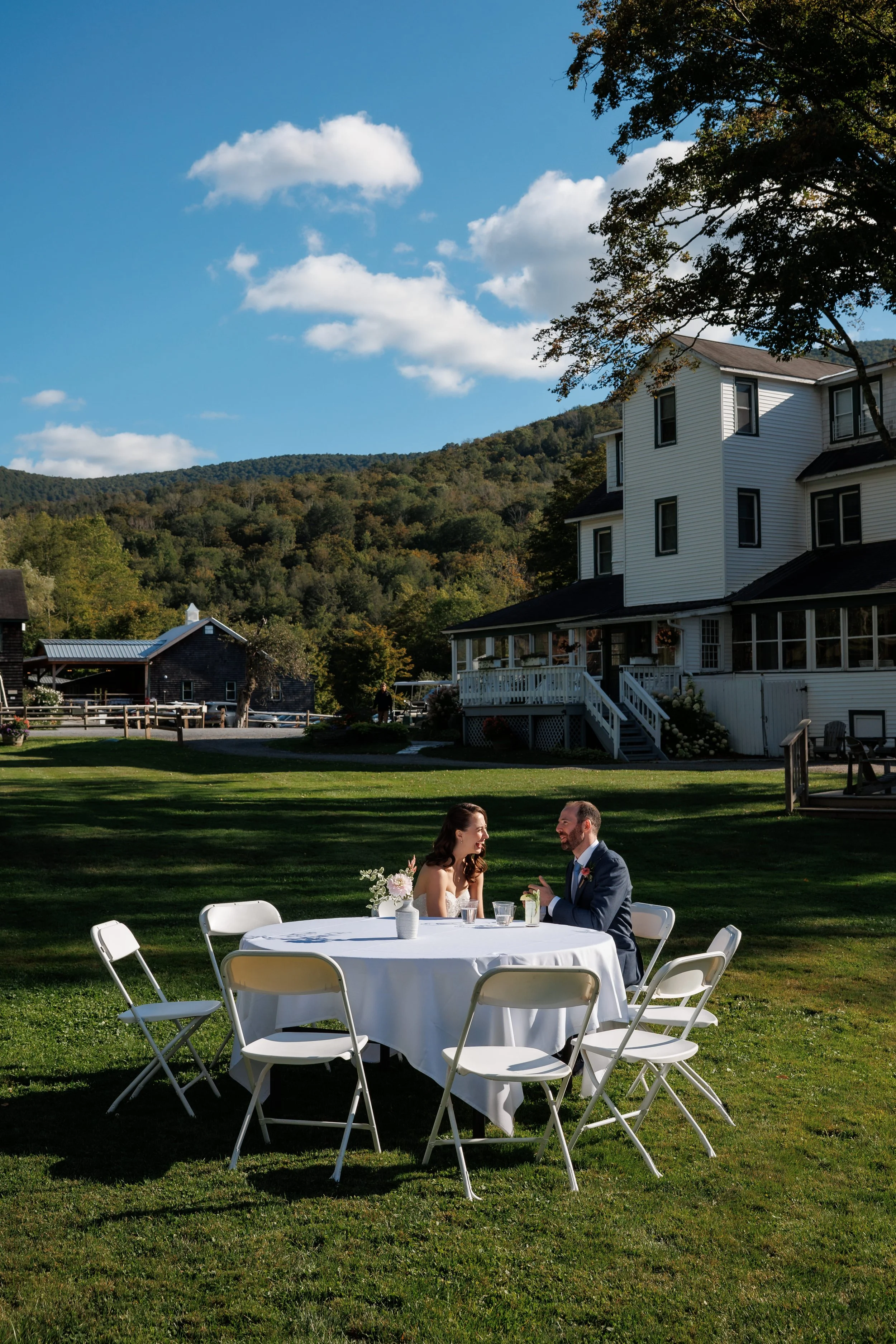 Couple sits at an outdoor table overlooking the Catskills after their wedding ceremony at Full Moon Resort