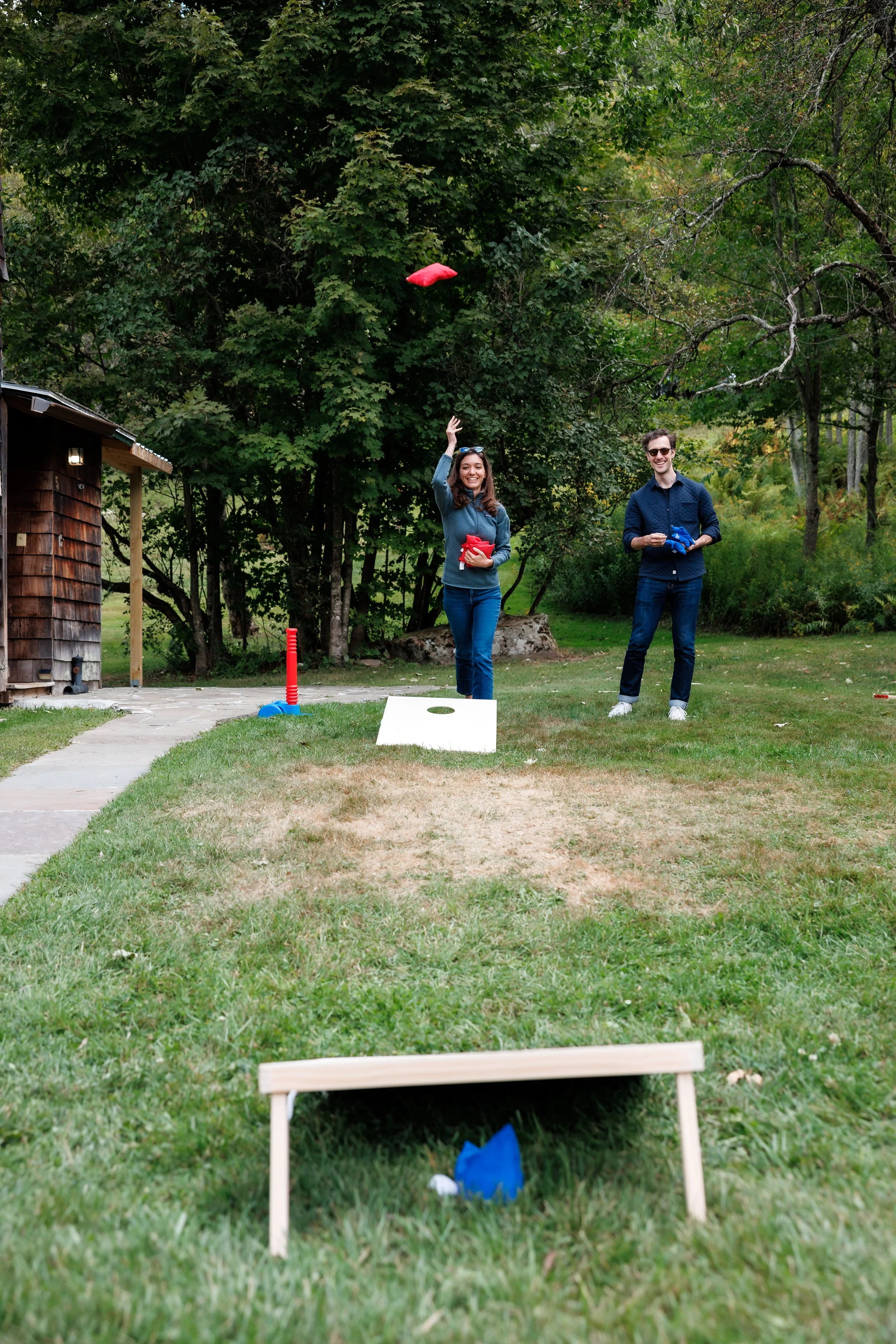 Couple tosses bean bags as they play cornhole during a weekend wedding at the Full Moon Resort
