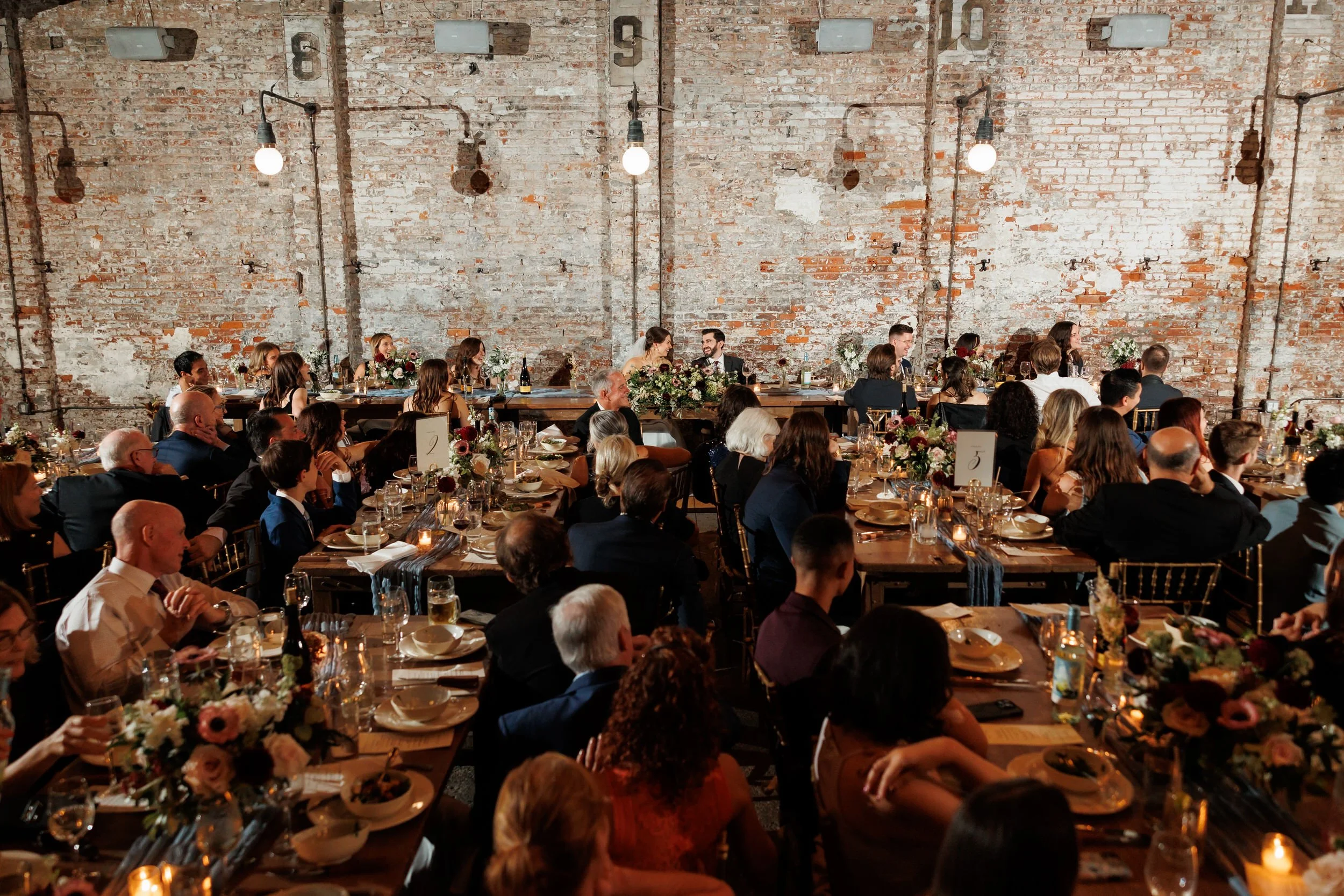 A large, industrial style room during a wedding reception 