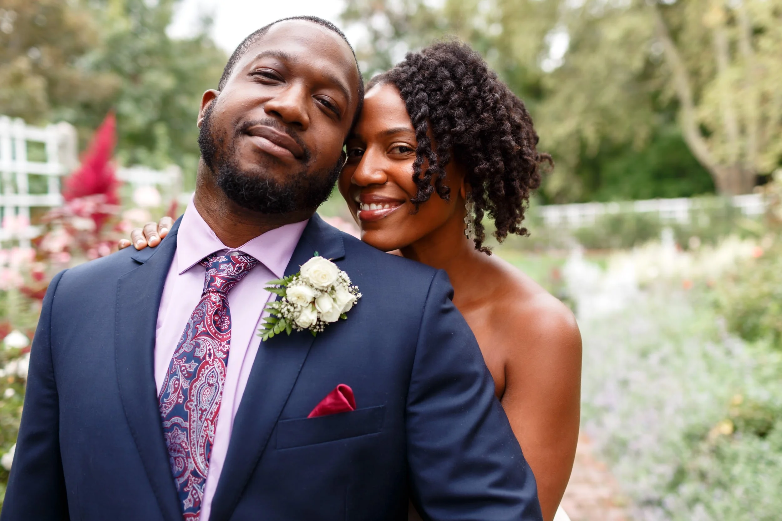 A person leaning back to rest their head on their partner's as they both smile 