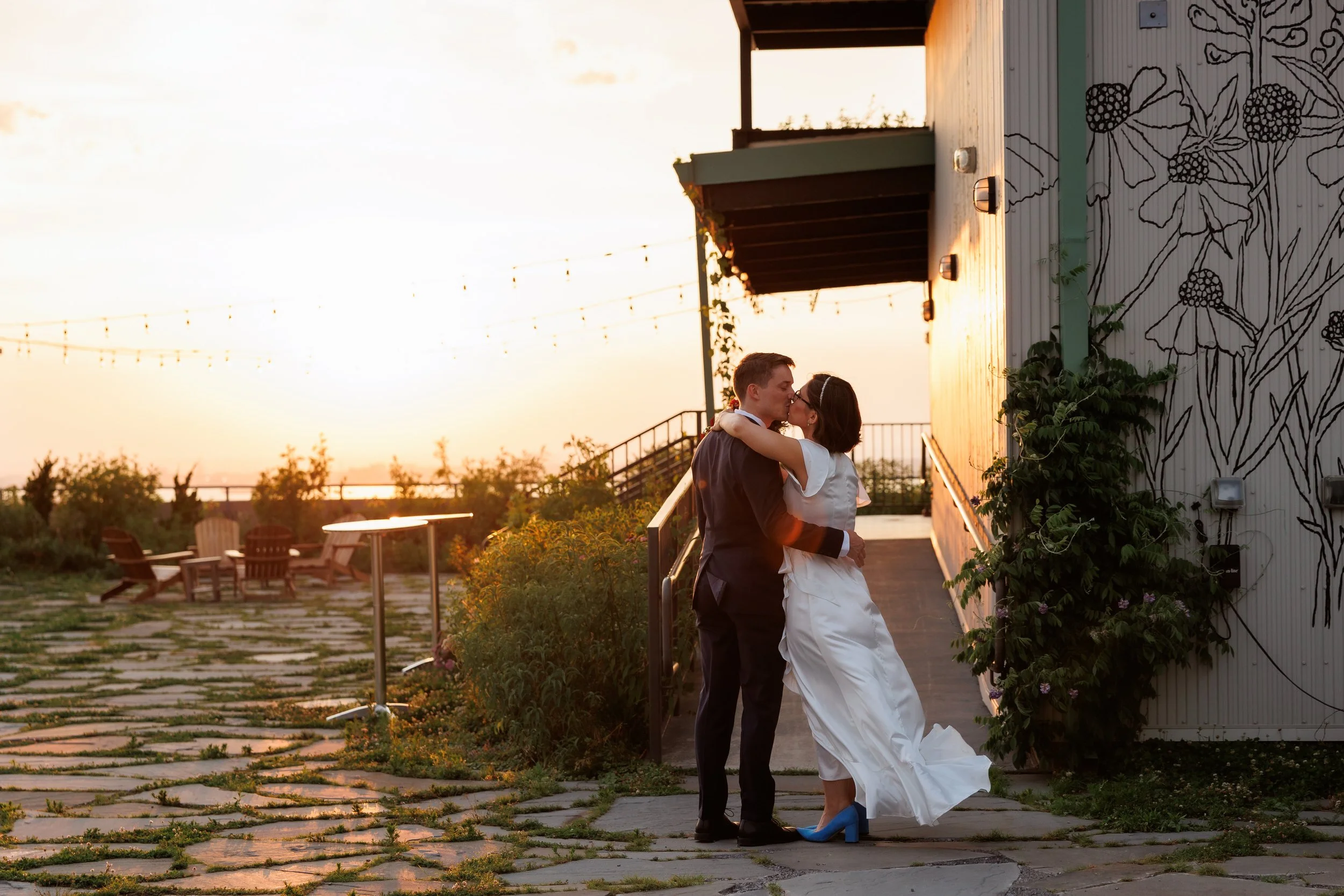 A newlywed couple kissing at the beach at sunset