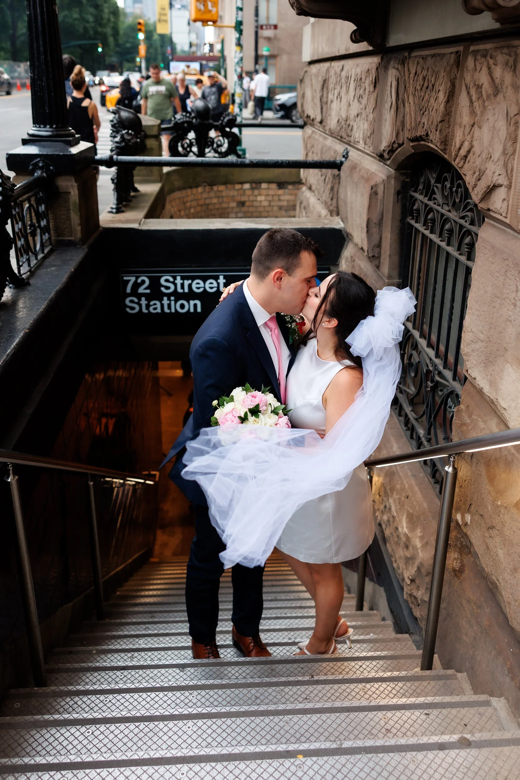 A newlywed couple kissing on the stairs to a subway