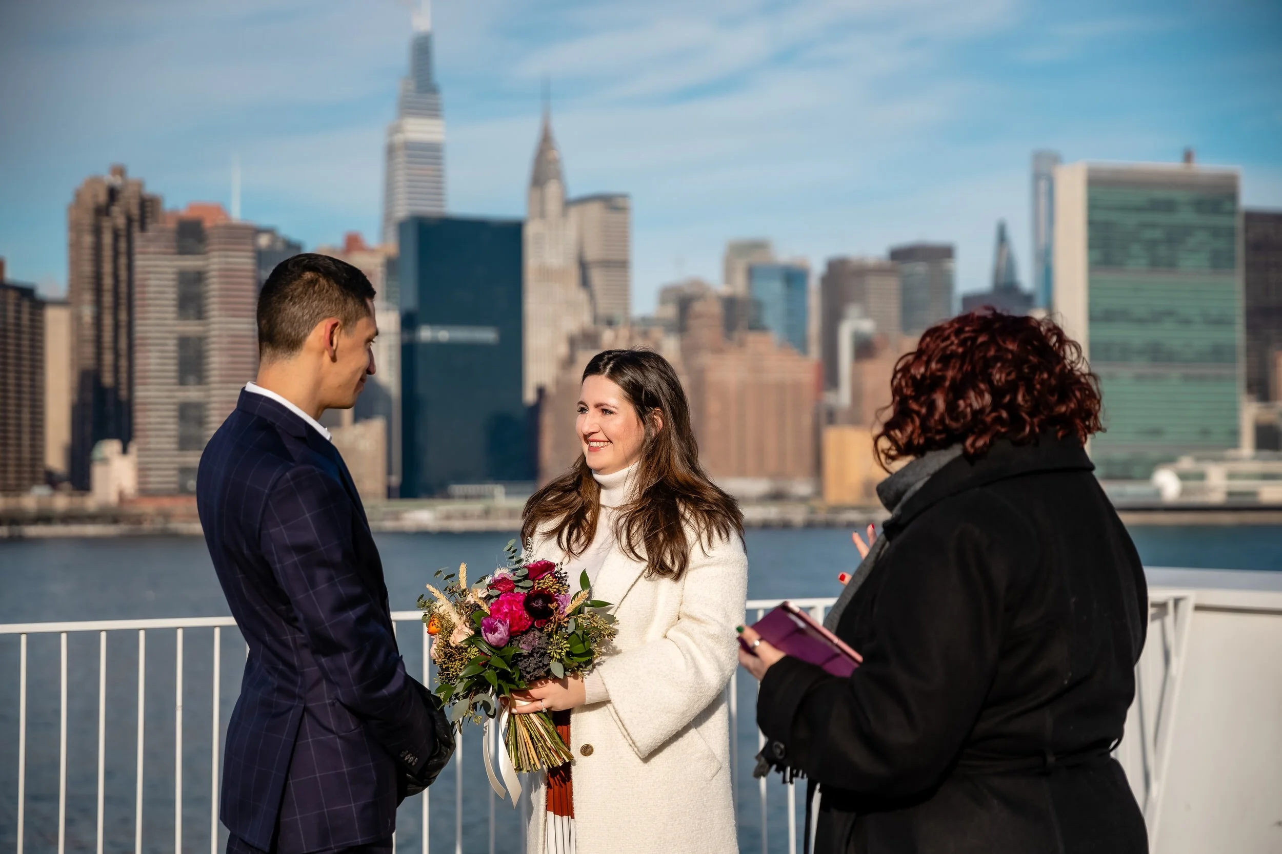 A wedding couple saying their vows with the city skyline behind them 