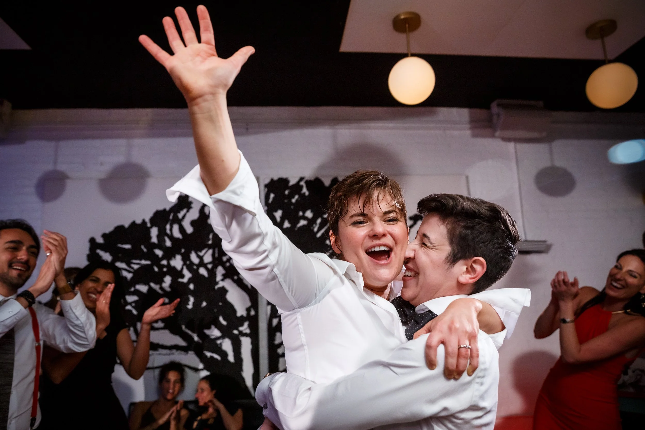 A person holding up their partner as they laugh and dance at their wedding reception 