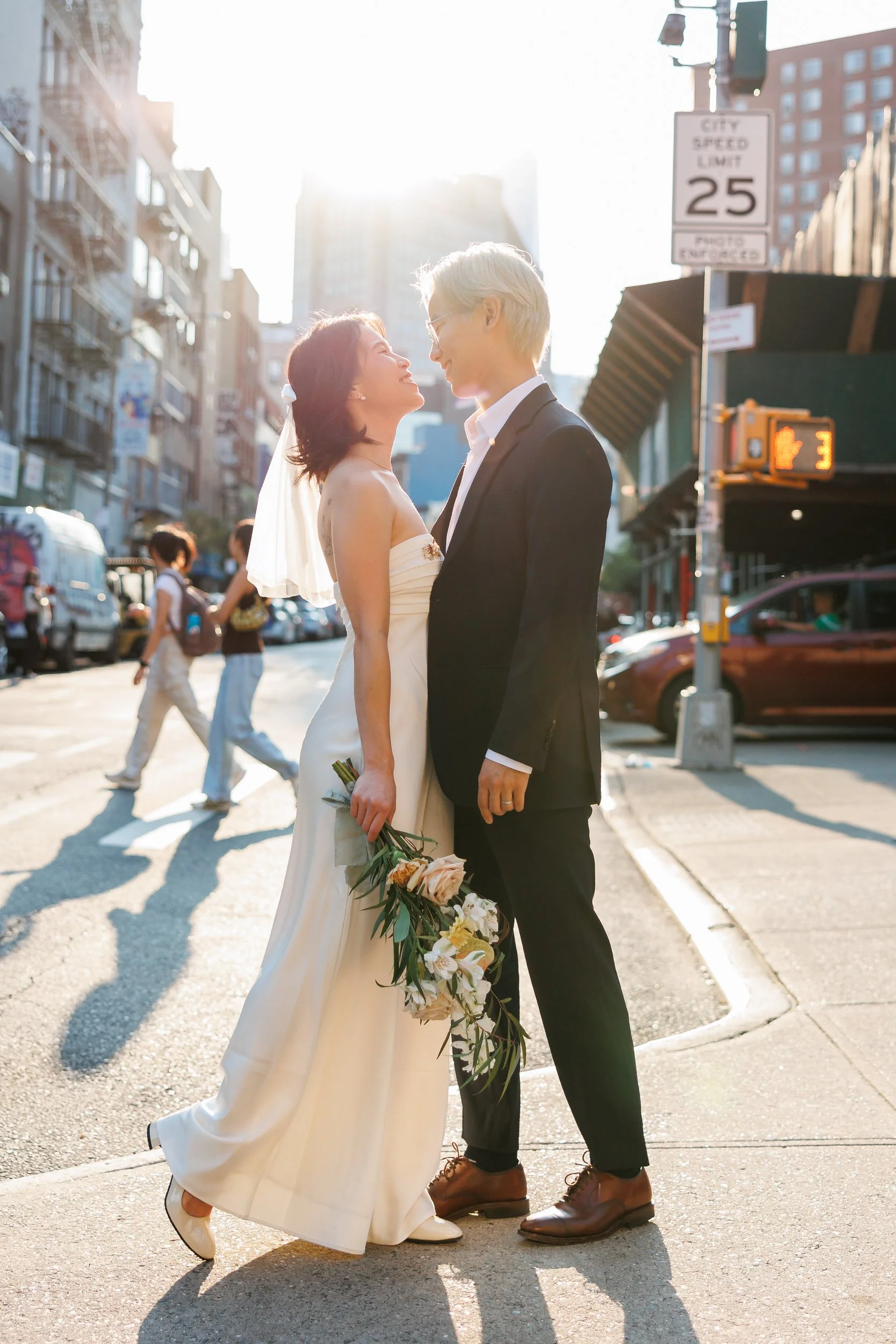 Newlyweds standing close together on the corner of a city sidewalk