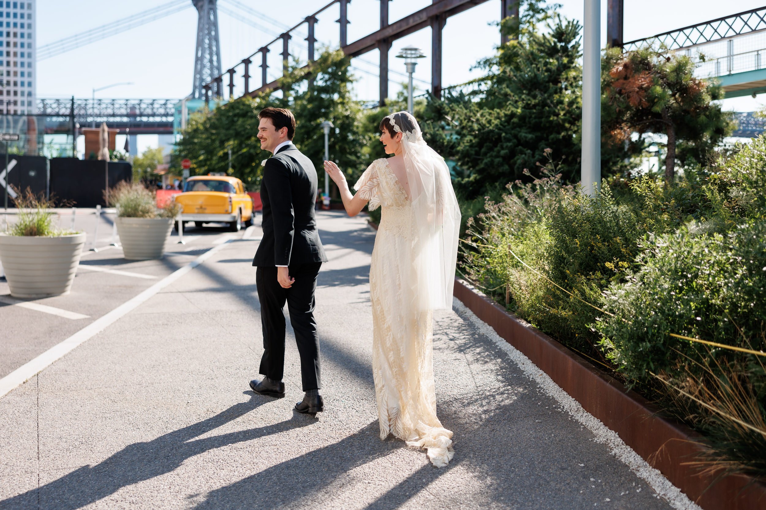 A wedding couple walking along a sidewalk in a city 
