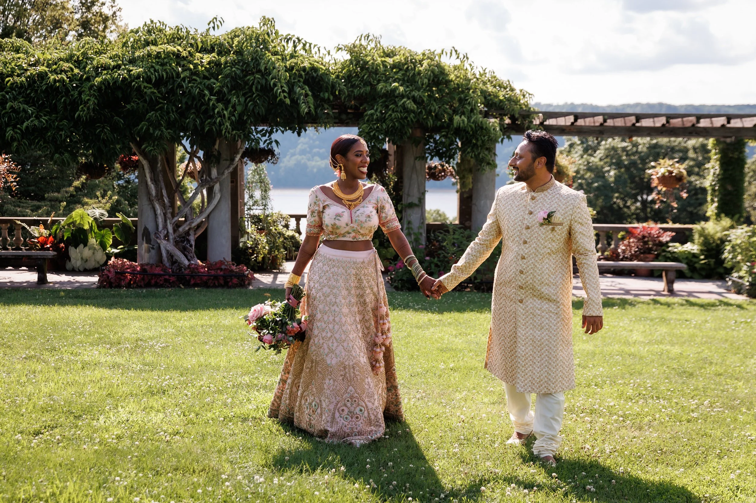 Newlyweds holding hands and walking together across the grass
