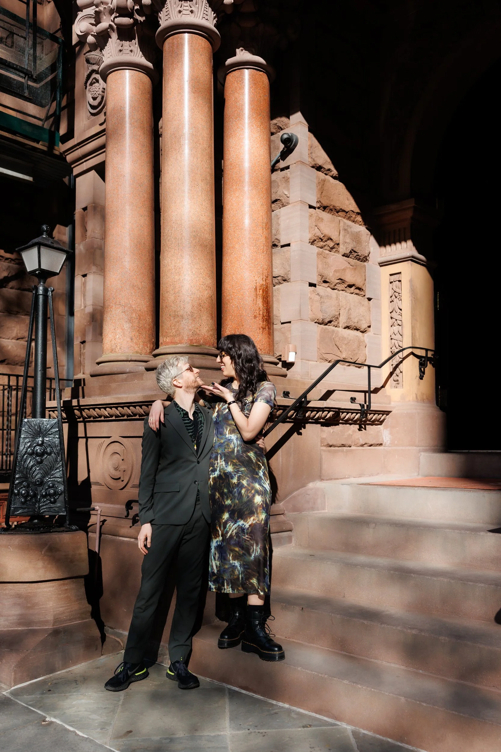 A person with their arm around their partner as they stand on a step below them.