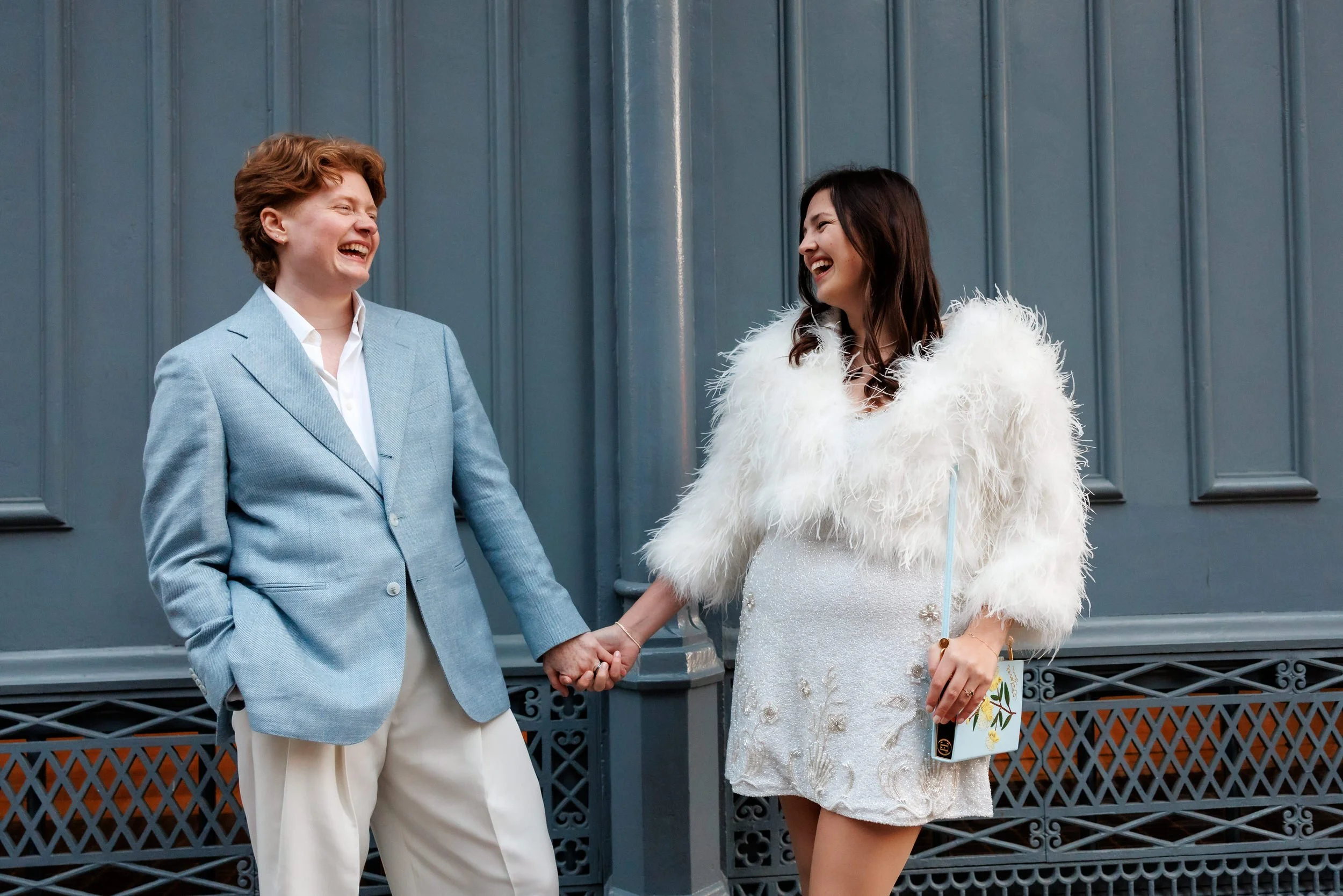 A couple holding hands and laughing as they lean in opposite directions 