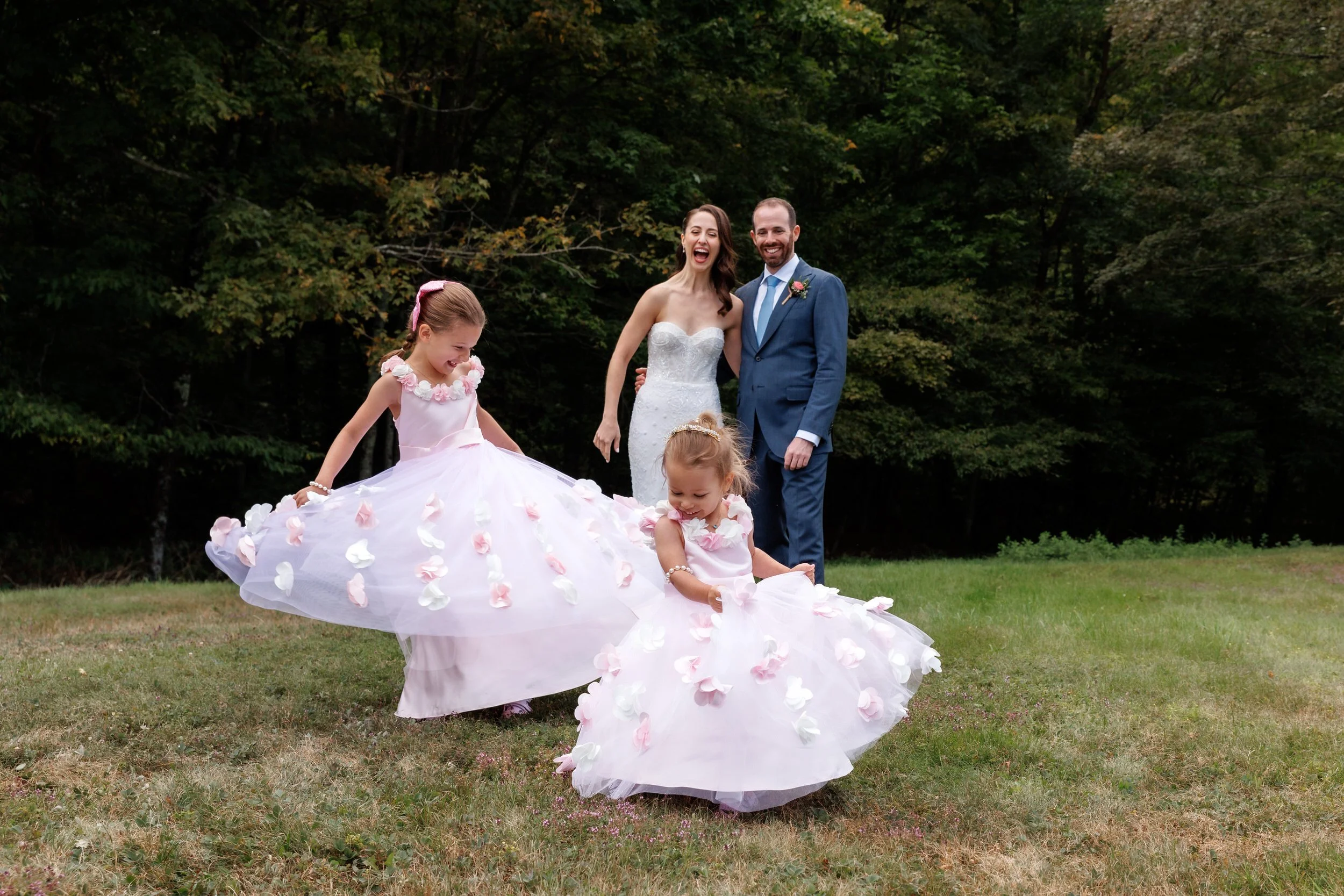 Newlyweds laughing as two young children play in front of them