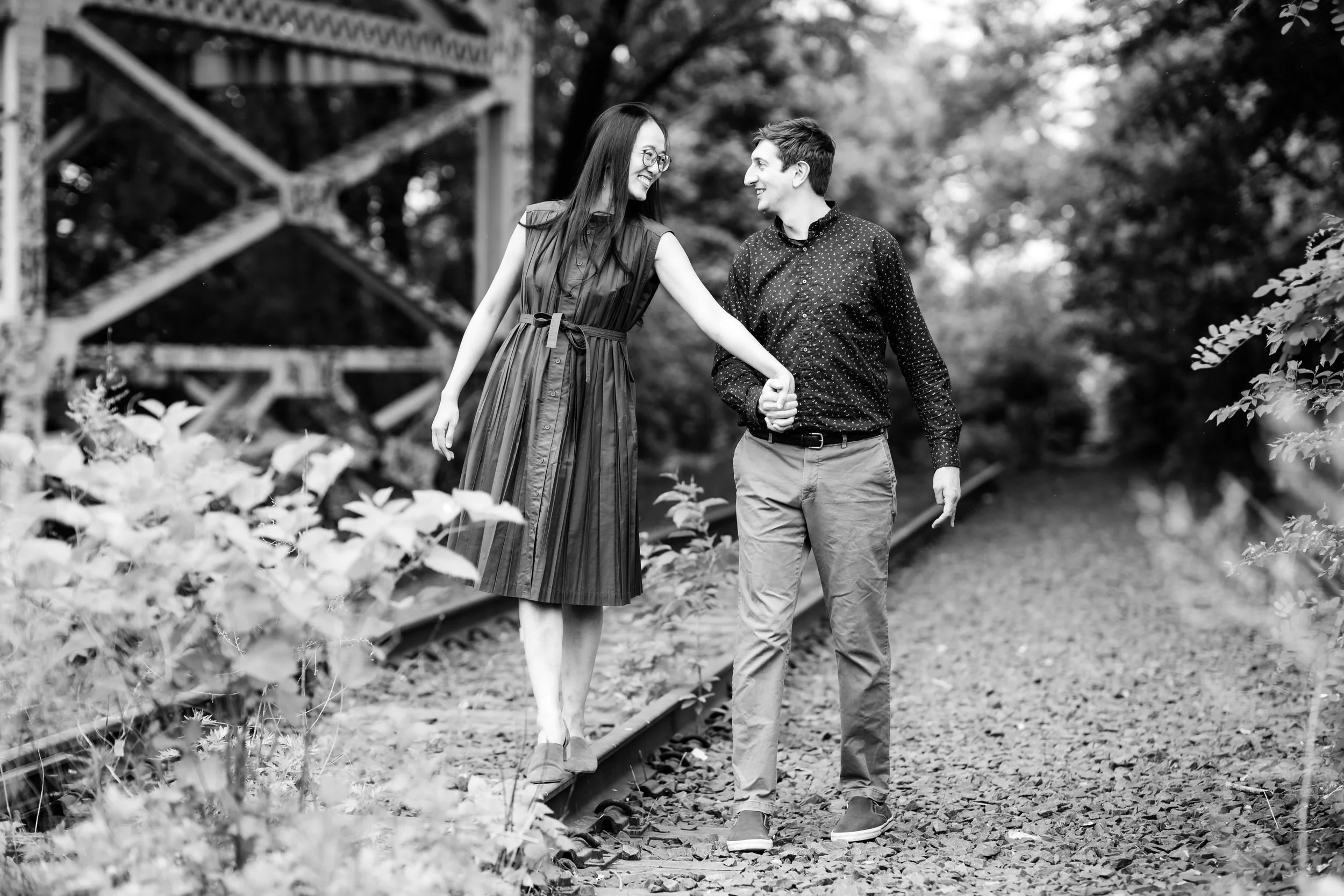 A couple holding hands and walking along train tracks 
