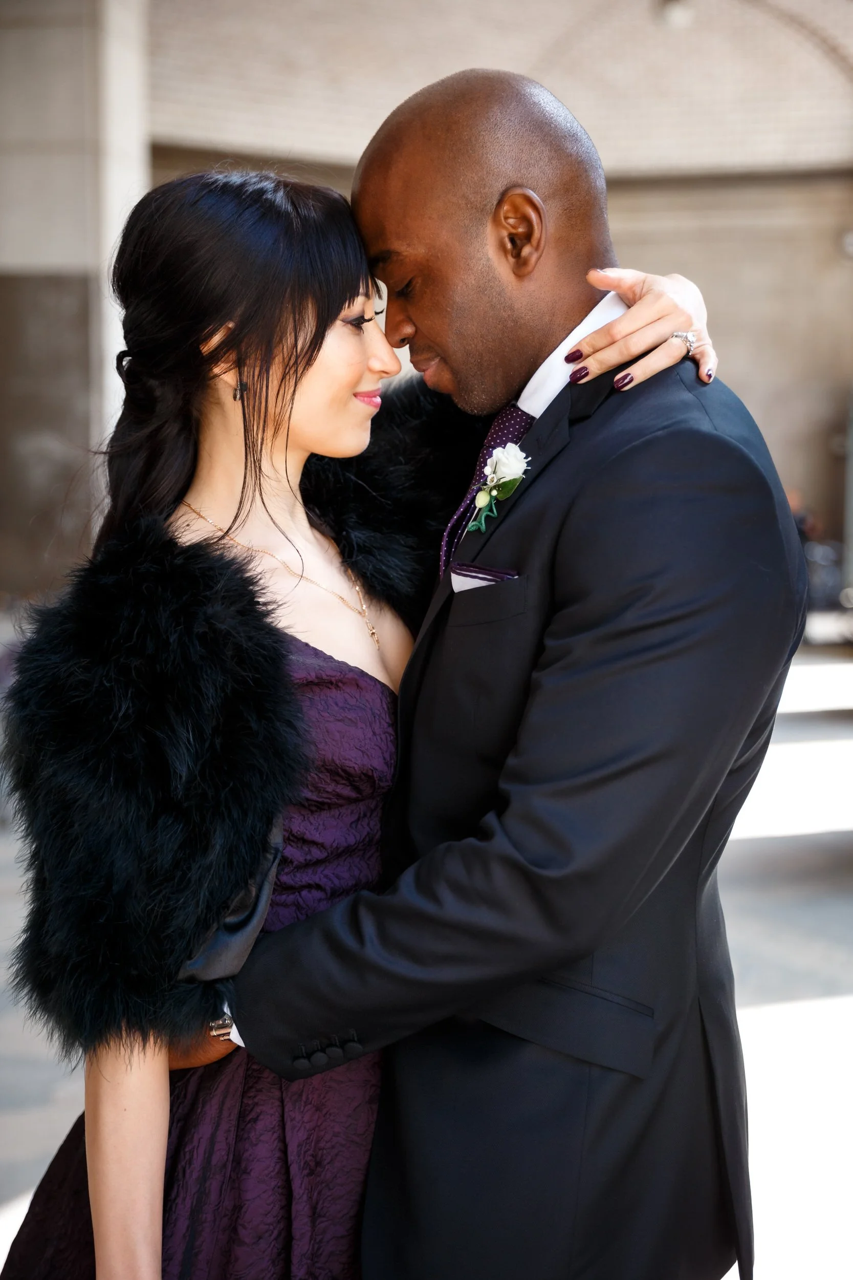 A wedding couple with their arms around each other standing forehead to forehead