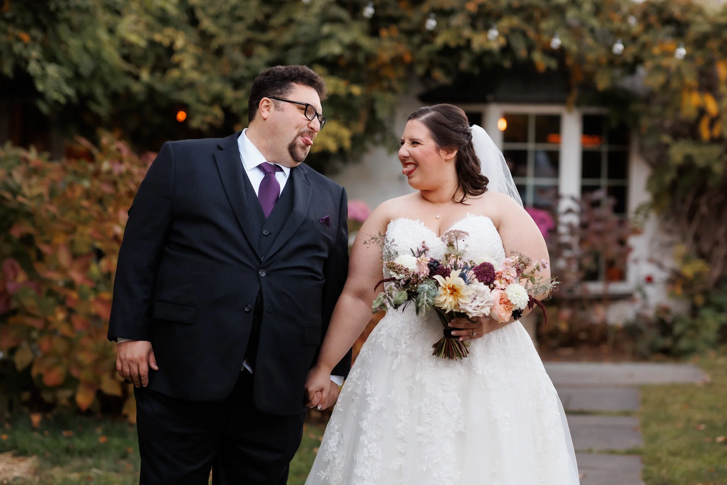 Newlyweds holding hands and sticking their tongues out at each other
