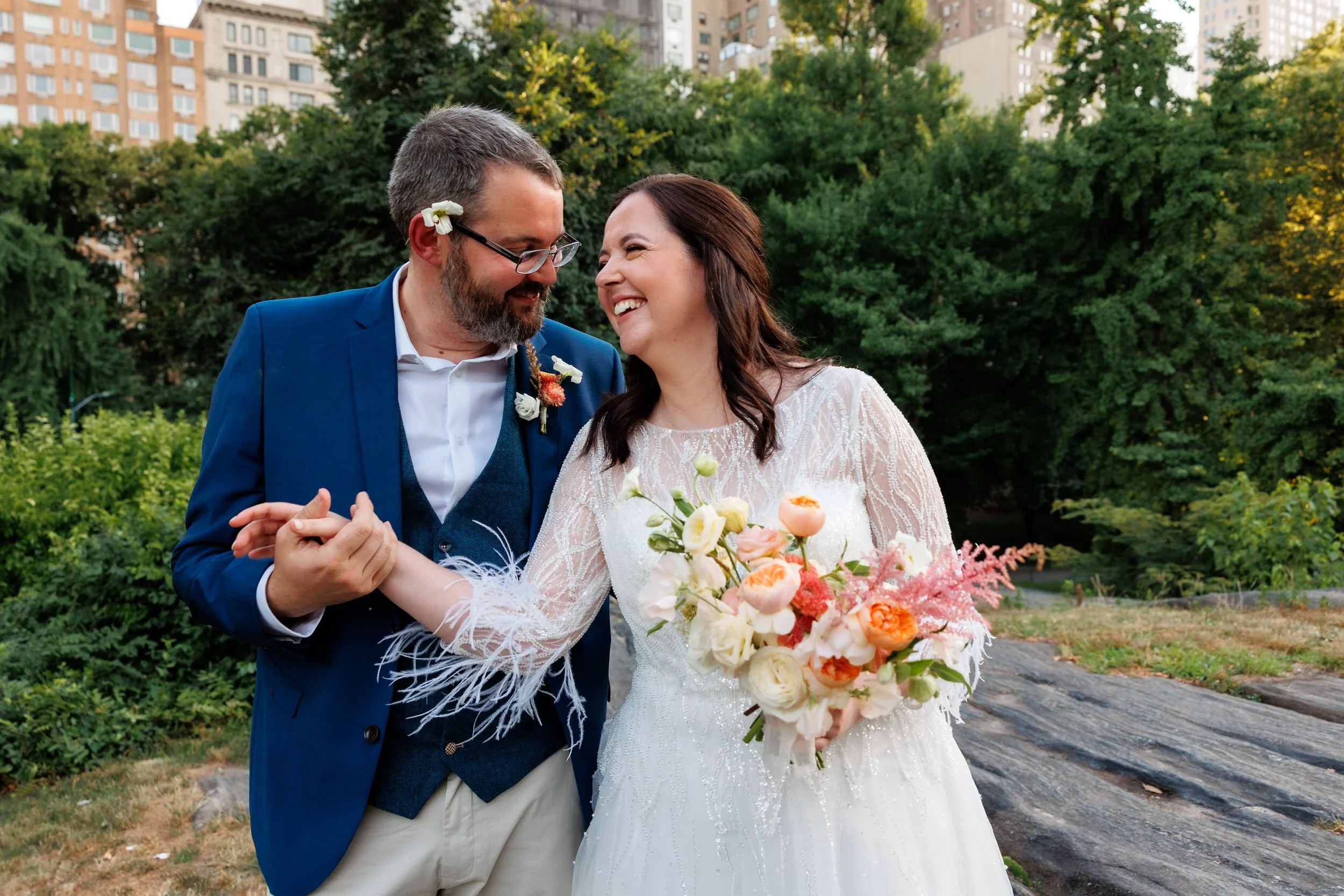 A newlywed couple leaning into each other and holding hands as they laugh 