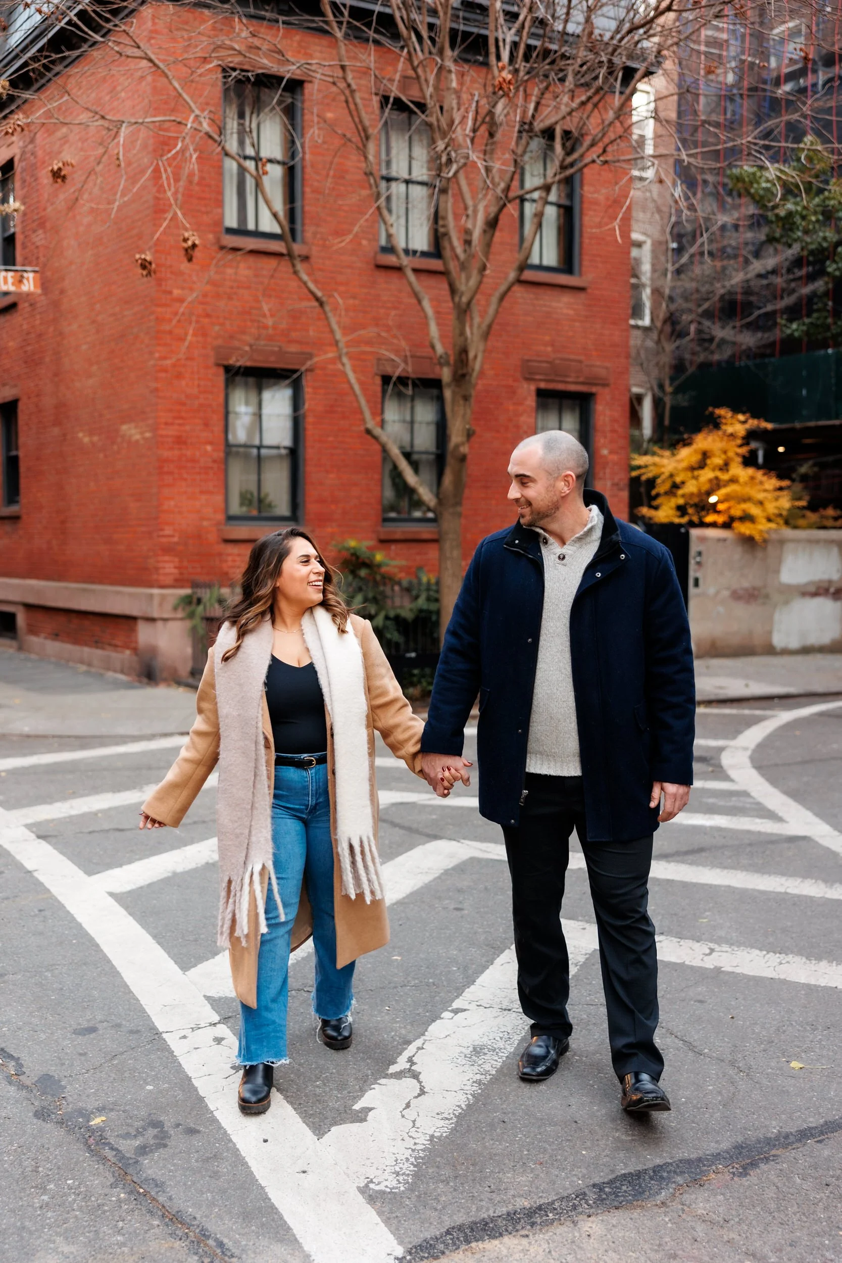 A couple holding hands and talking as they walk across the street 