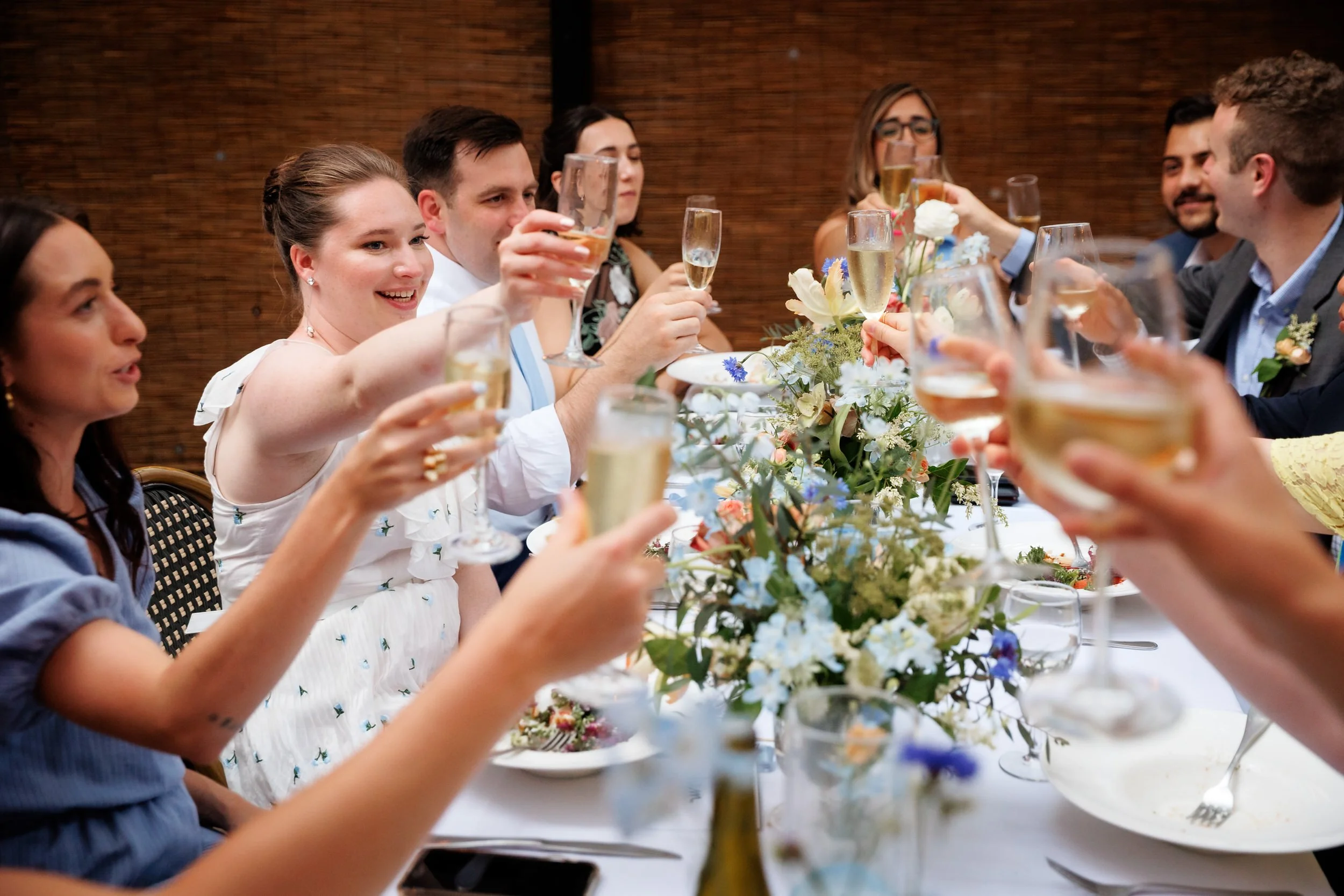 Newlyweds and their guests holding up champagne glasses in a toast 