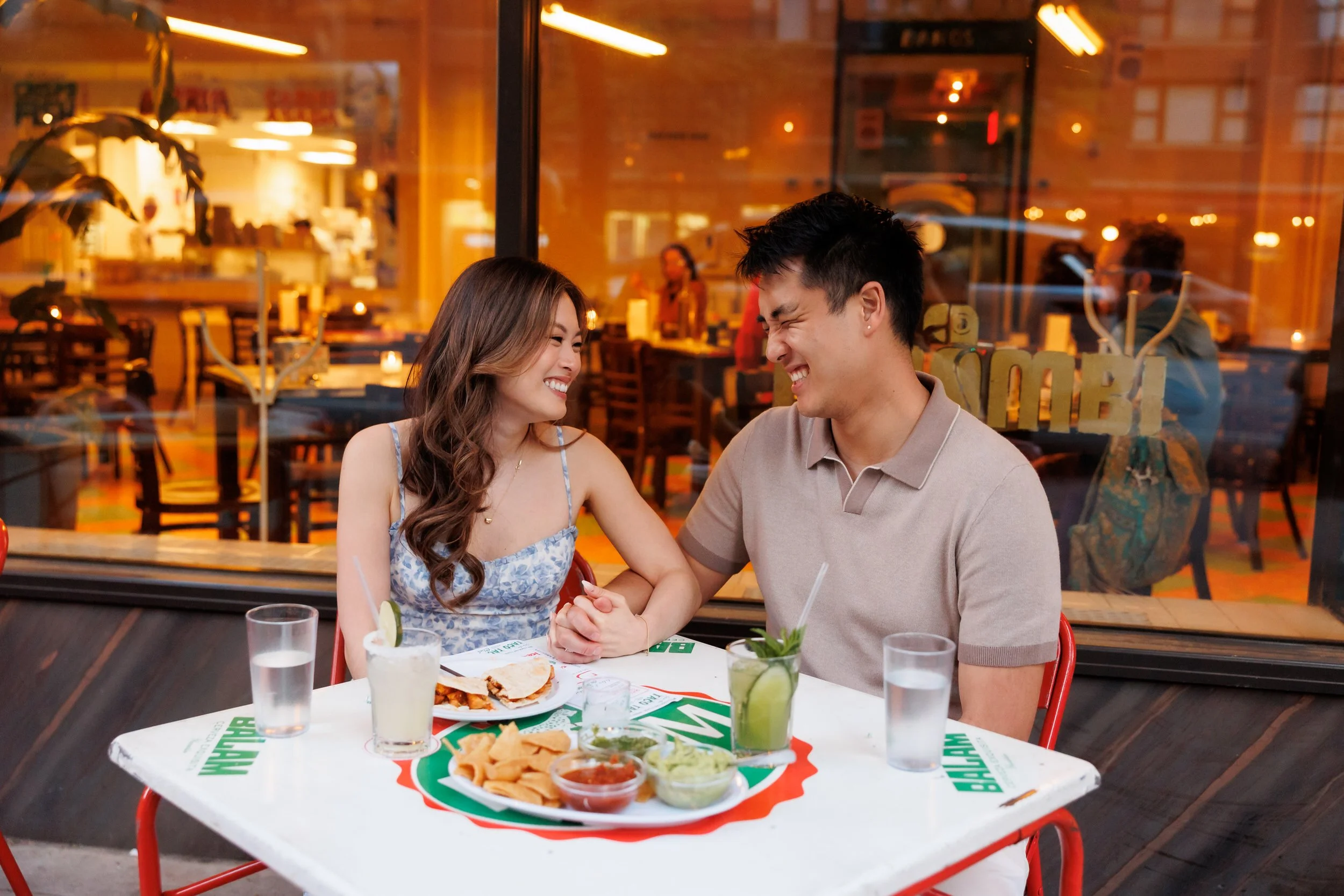 A couple sitting together at a restaurant holding hands