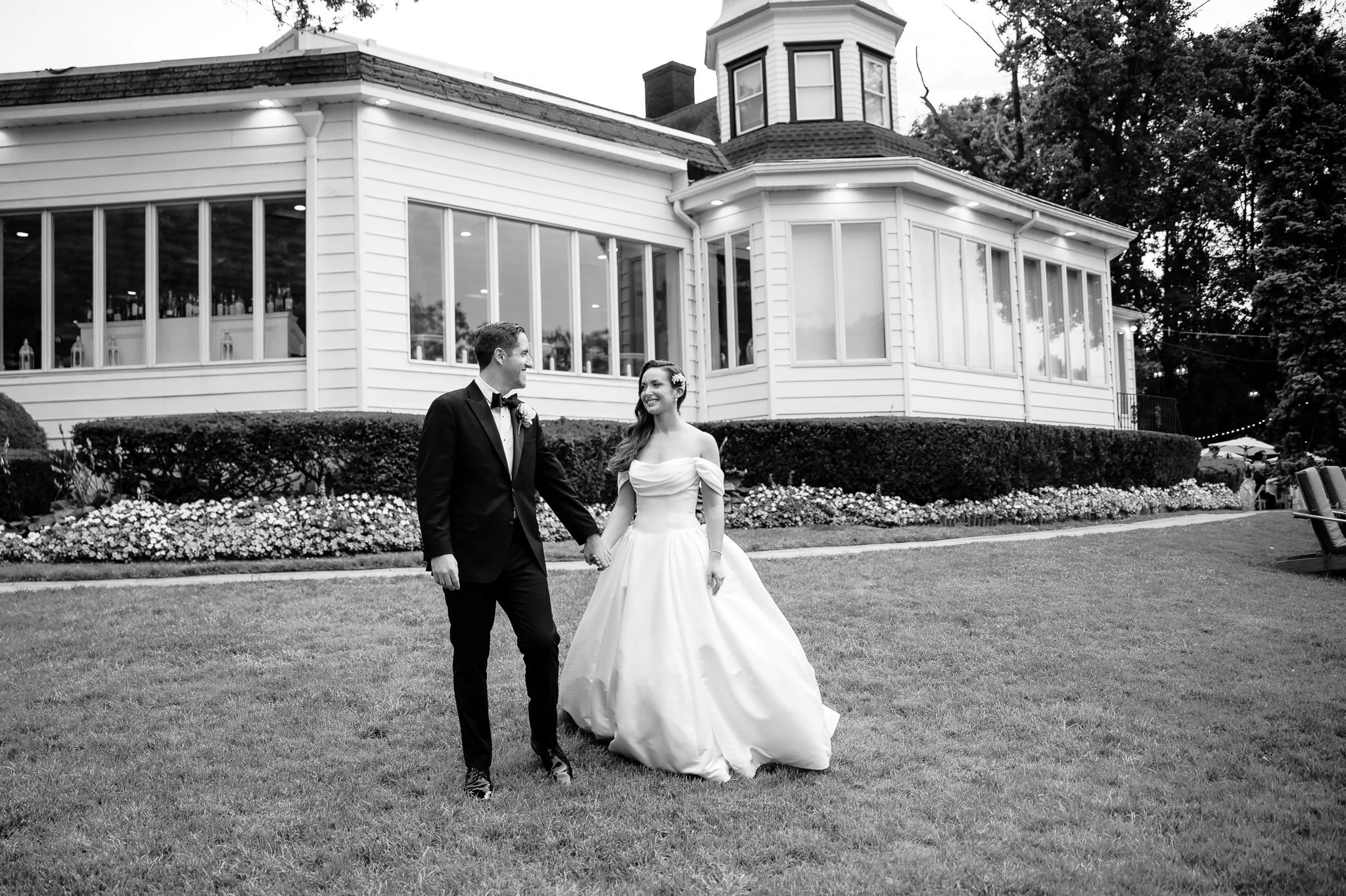 couple holds hands and walks in front of long island venue on their wedding day