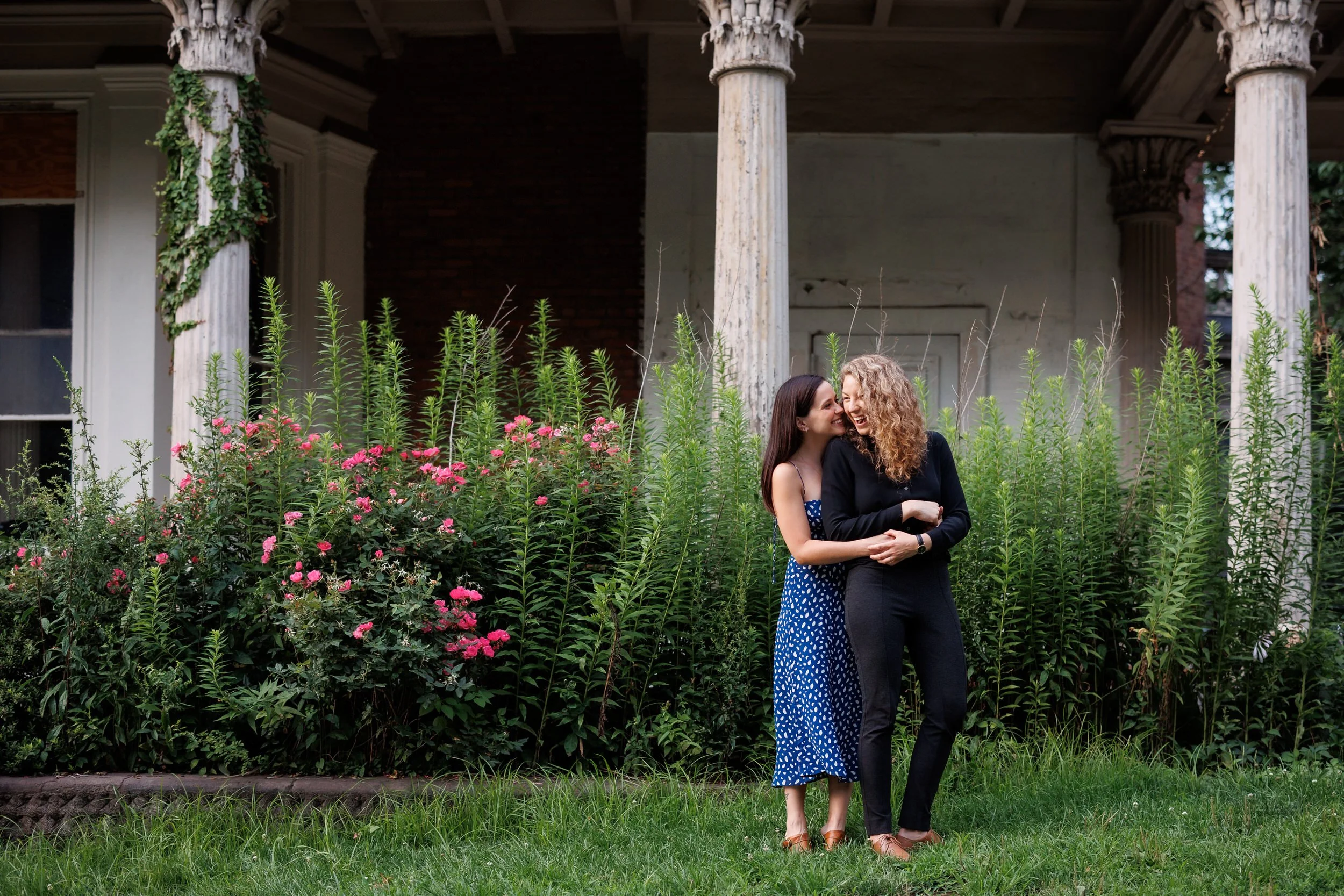 A person hugging their partner from behind while standing in a garden area 