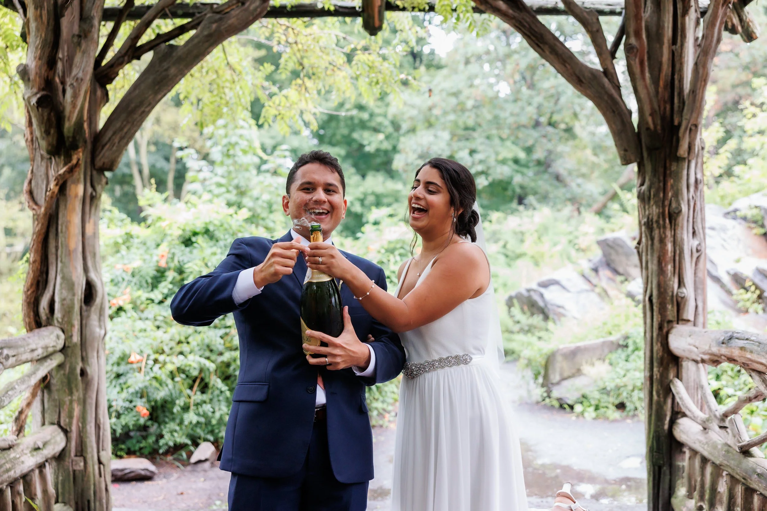 Newlyweds popping a bottle of champagne together 