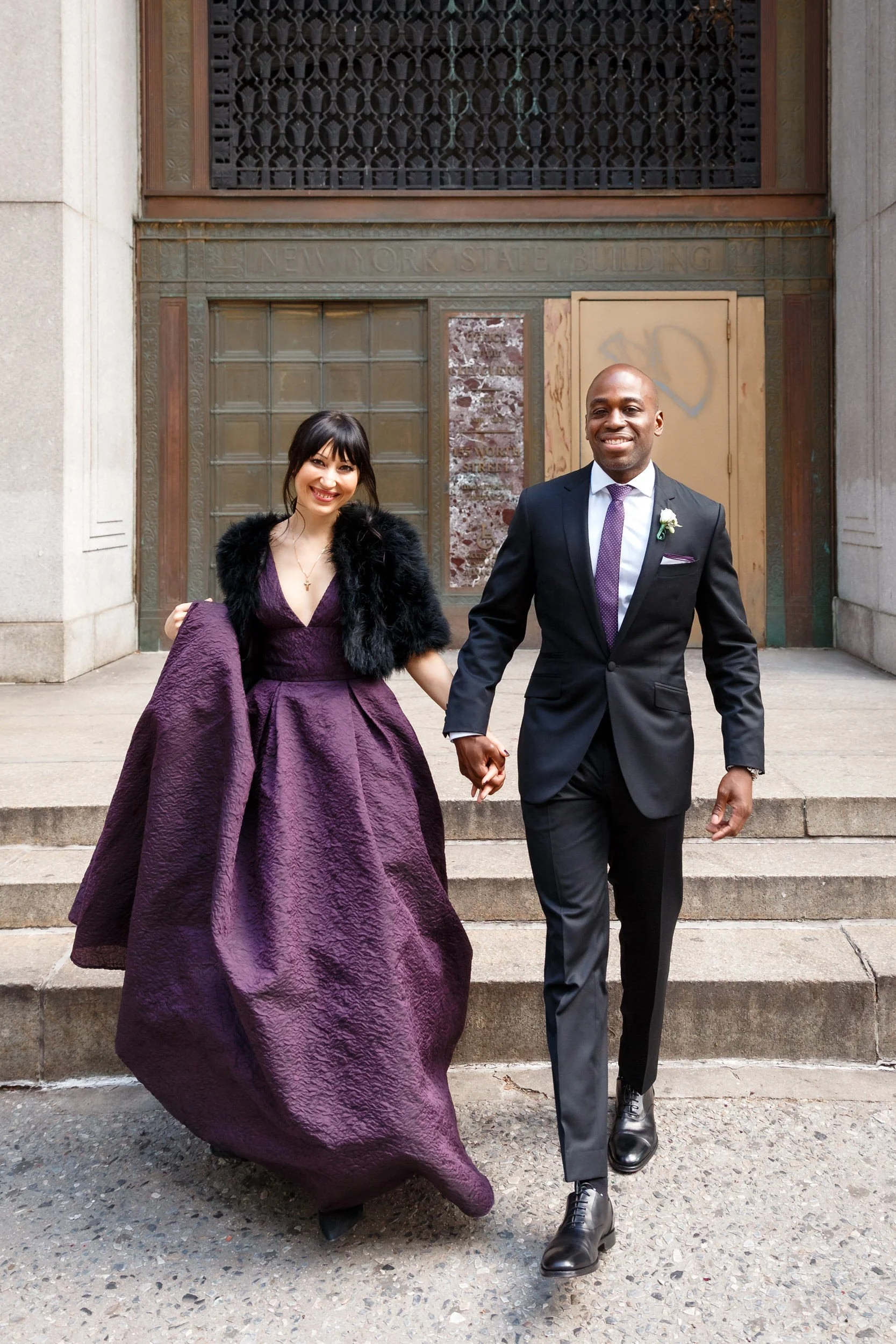 Newlyweds holding hands and walking down the stairs together
