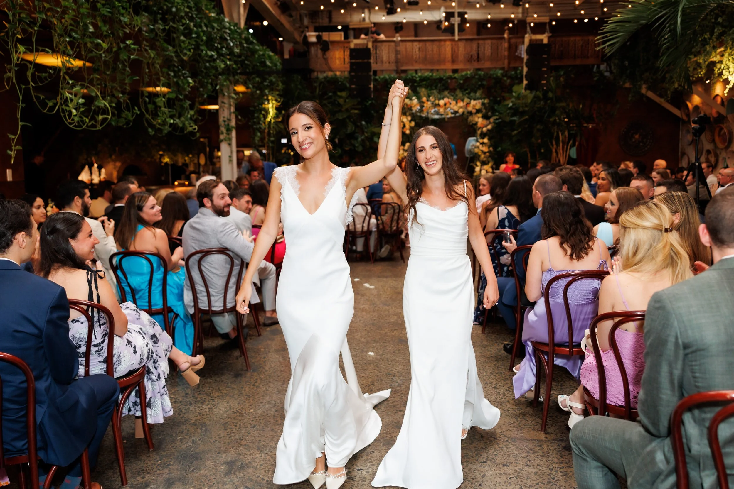 Newlyweds with their linked hands in the air as they walk back up the aisle 