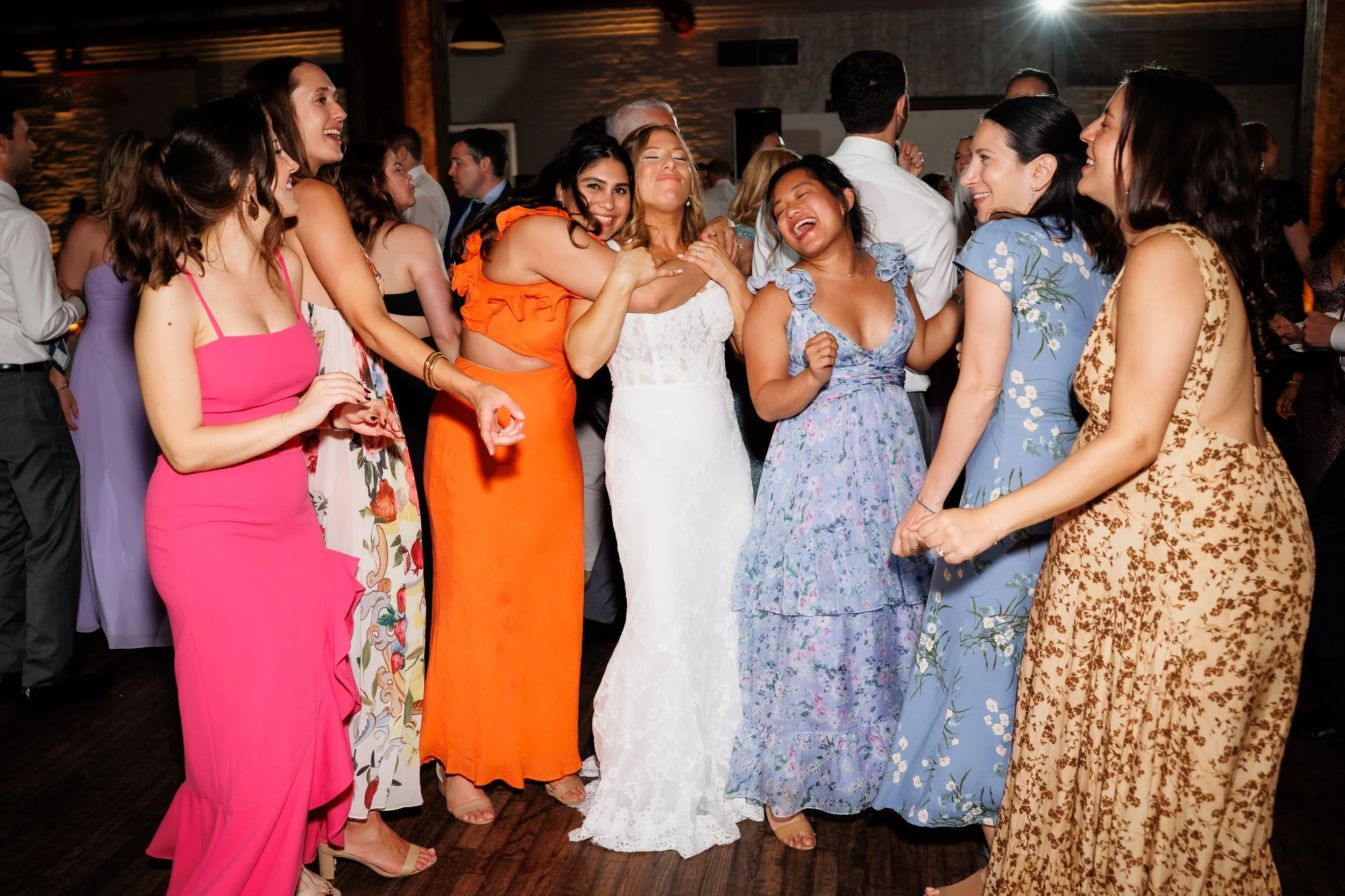 Wedding guests dancing with a newlywed at their reception 