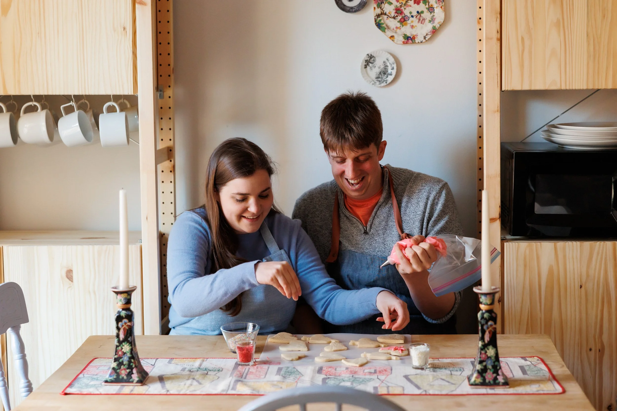 A couple sitting at a table together decorating cookies 