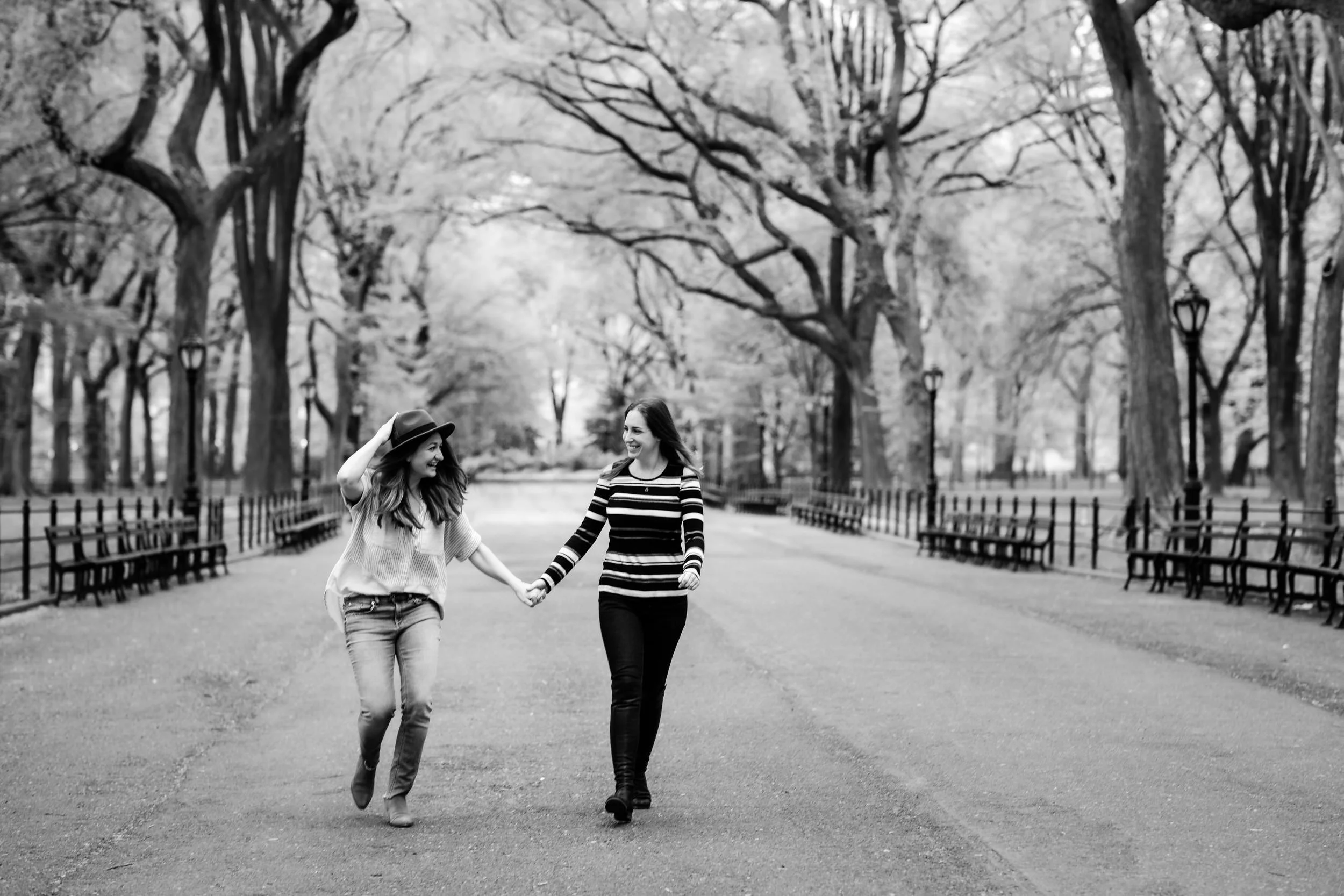 A couple holding hands and laughing as they walk in a park 