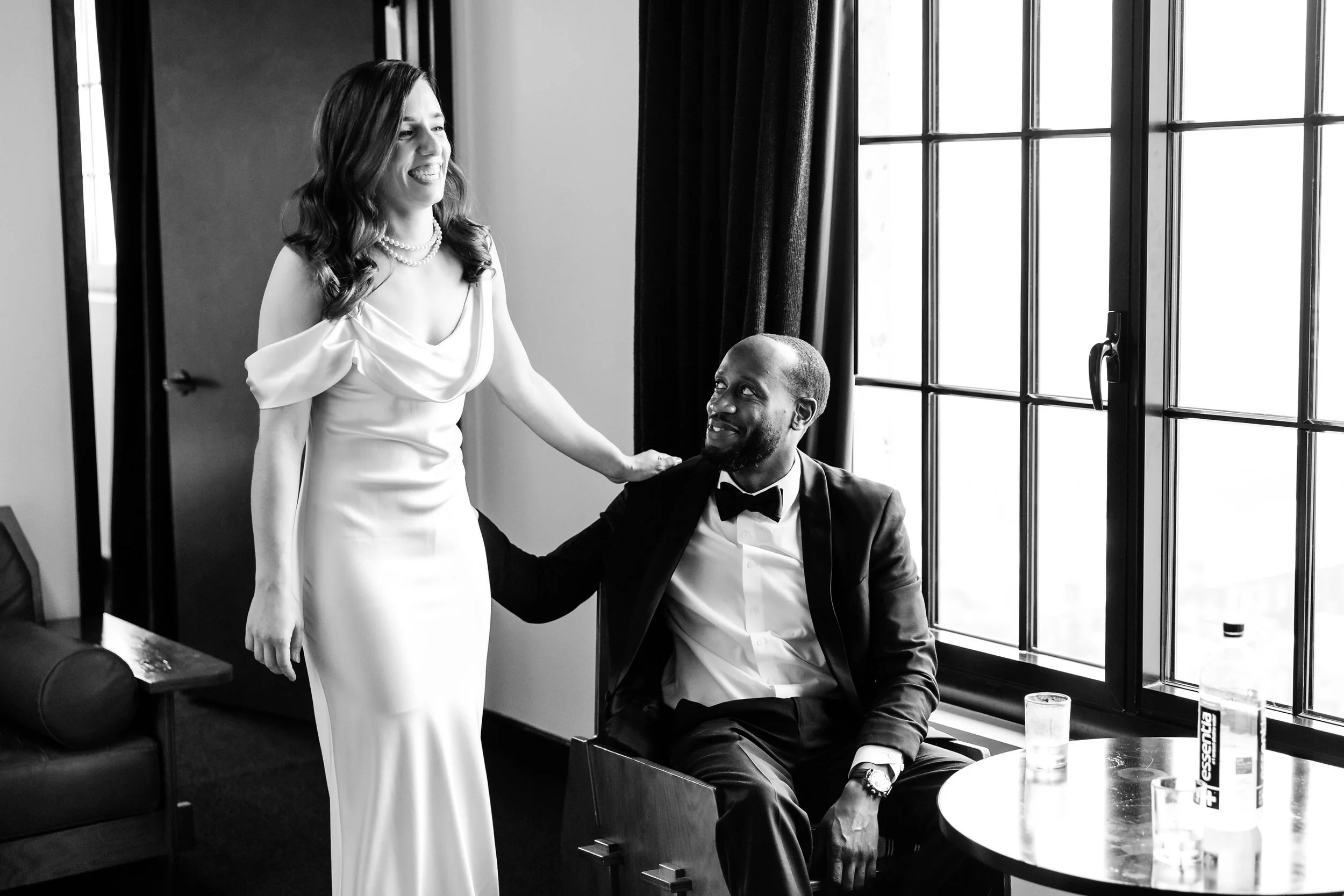 A person sitting down with their hand on their partner's hip who is standing next to them 