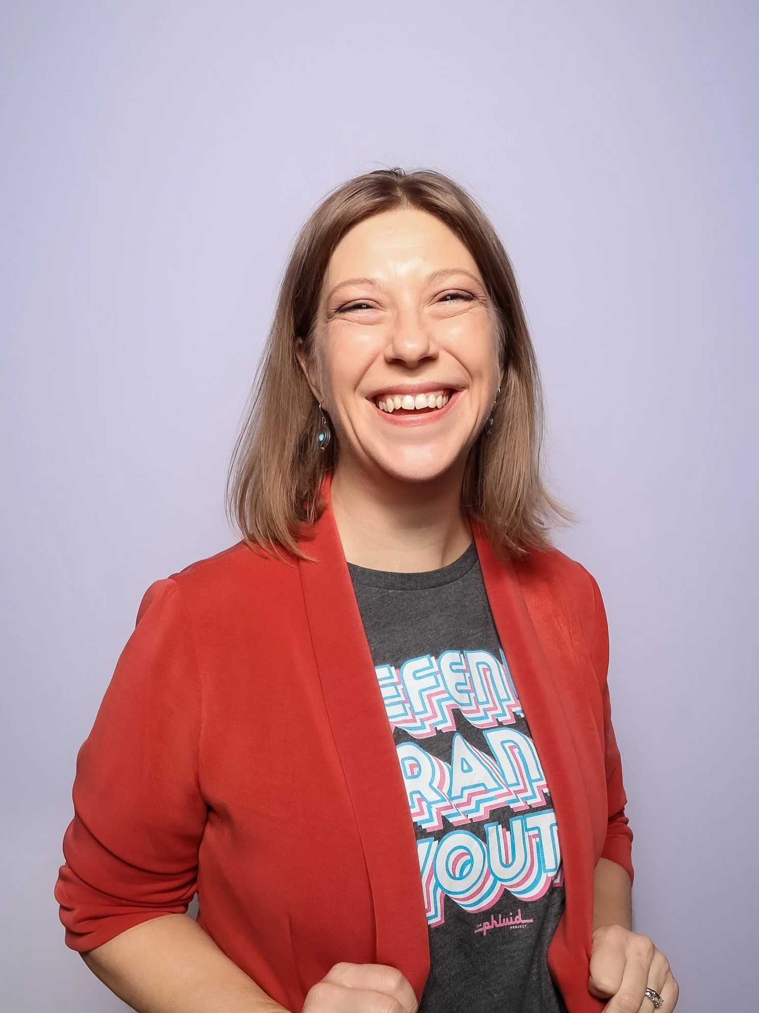 Sarah smiling while holding either side of her blazer