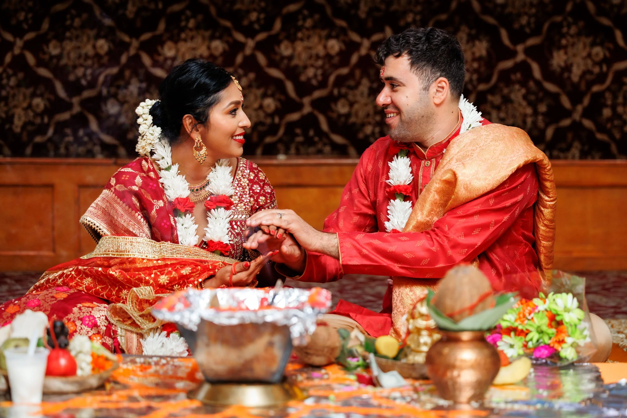 Newlyweds sitting on the ground together holding hands 