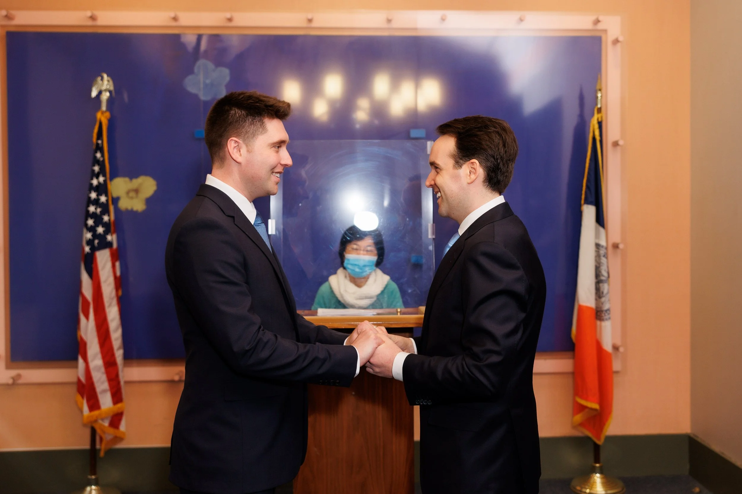 Two people in suits holding hands and exchanging vows 